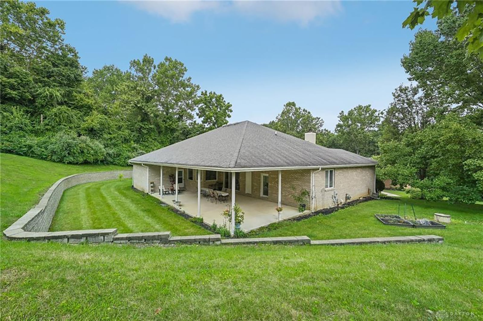 The rear of the home has an oversized concrete covered patio with ceiling lighting. there is also an additional brick retaining wall surrounding most of the home in the rear.