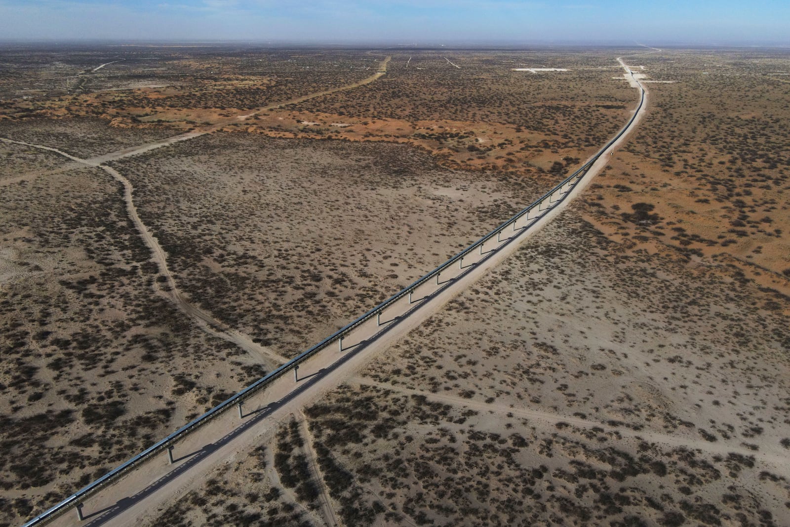 With New Mexico seen at a distance, a 42-mile conveyor belt by Atlas Energy carries sand needed for hydraulic fracturing Wednesday, Feb. 26, 2025, in Kermit, Texas. (AP Photo/Julio Cortez)