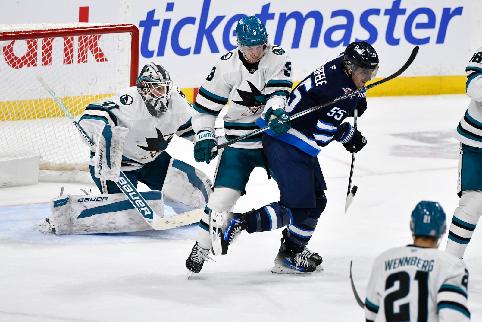 Winnipeg Jets' Mark Scheifele (55) deflects an incoming shot in front of San Jose Sharks goaltender Vitek Vanecek (41) and Henry Thrun (3) during third-period NHL hockey game action in Winnipeg, Manitoba, Monday, Feb. 24, 2025. (Fred Greenslade/The Canadian Press via AP)