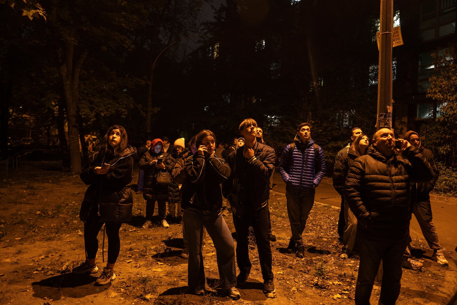 Local residents watch a residential building burn after an attack of Russian drones killed a teenager in Kyiv, Ukraine, Friday, Oct. 25, 2024. (AP Photo/Alex Babenko)