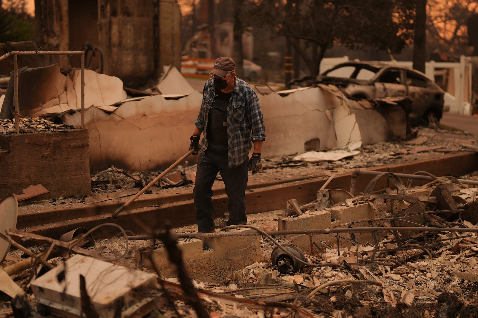 Paul Perri searches through his daughter's fire-ravaged property in the aftermath of the Eaton Fire Thursday, Jan. 9, 2025 in Altadena, Calif. (AP Photo/Eric Thayer)