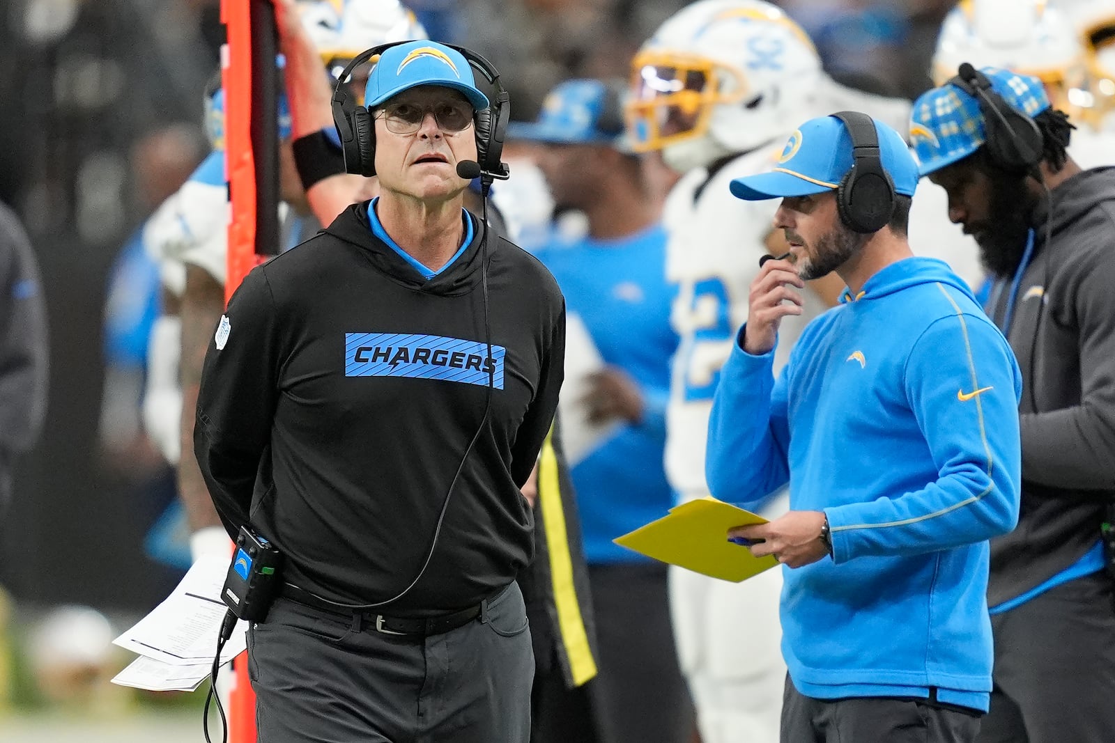 Los Angeles Chargers head coach Jim Harbaugh, left, walks on the sideline during the first half of an NFL football game against the Las Vegas Raiders in Las Vegas, Sunday, Jan. 5, 2025. (AP Photo/John Locher)