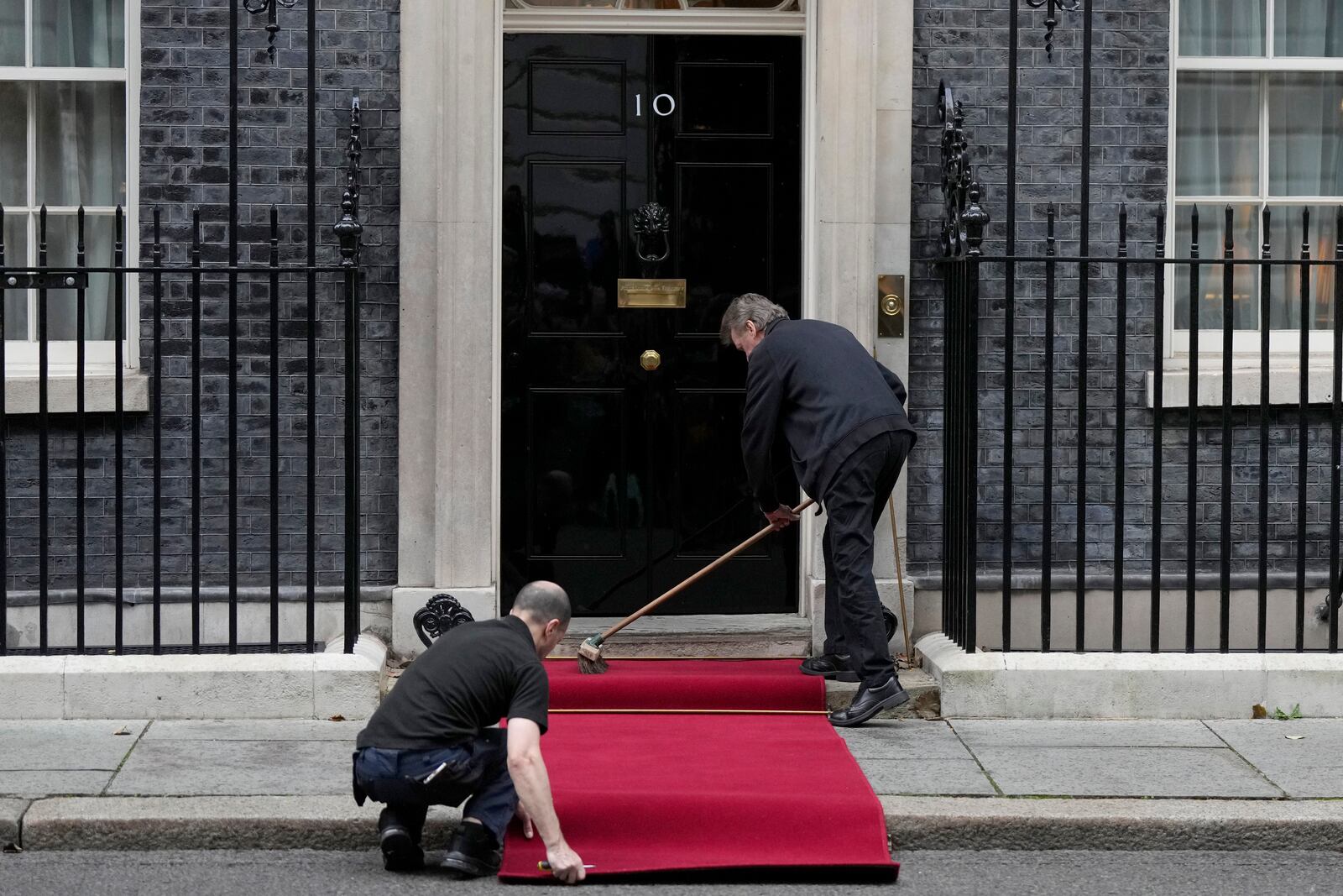 Staff members prepare the red carpet for the arrival of Ukrainian President Volodymyr Zelenskyy and NATO Secretary General Mark Rutte to 10 Downing Street in London, Thursday, Oct. 10, 2024.(AP Photo/Alastair Grant)