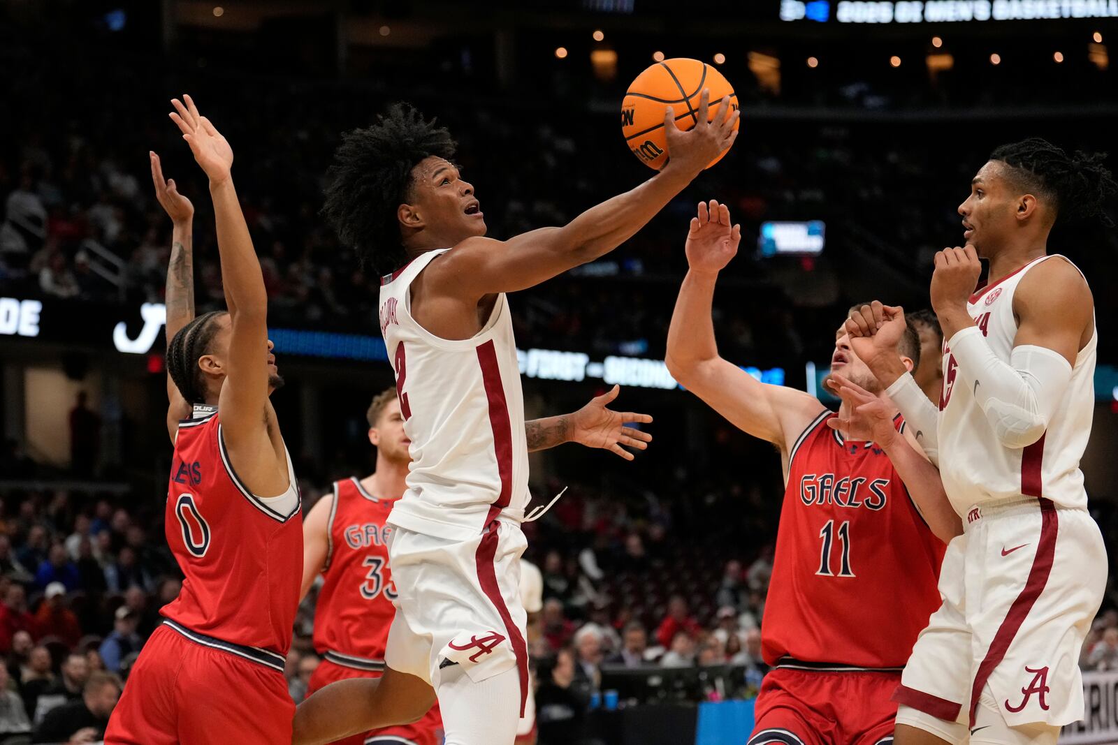 Alabama guard Aden Holloway (2) goes to the basket between Saint Mary's guard Mikey Lewis (0) and center Mitchell Saxen (11) in the first half in the second round of the NCAA college basketball tournament, Sunday, March 23, 2025, in Cleveland. (AP Photo/Sue Ogrocki)