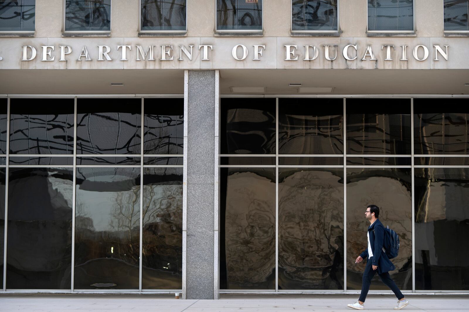 A commuter walks past the headquarters of the U.S. Department of Eduction, which were ordered closed for the day for what officials described as security reasons amid large-scale layoffs, Wednesday, March 12, 2025, in Washington. (AP Photo/Mark Schiefelbein)