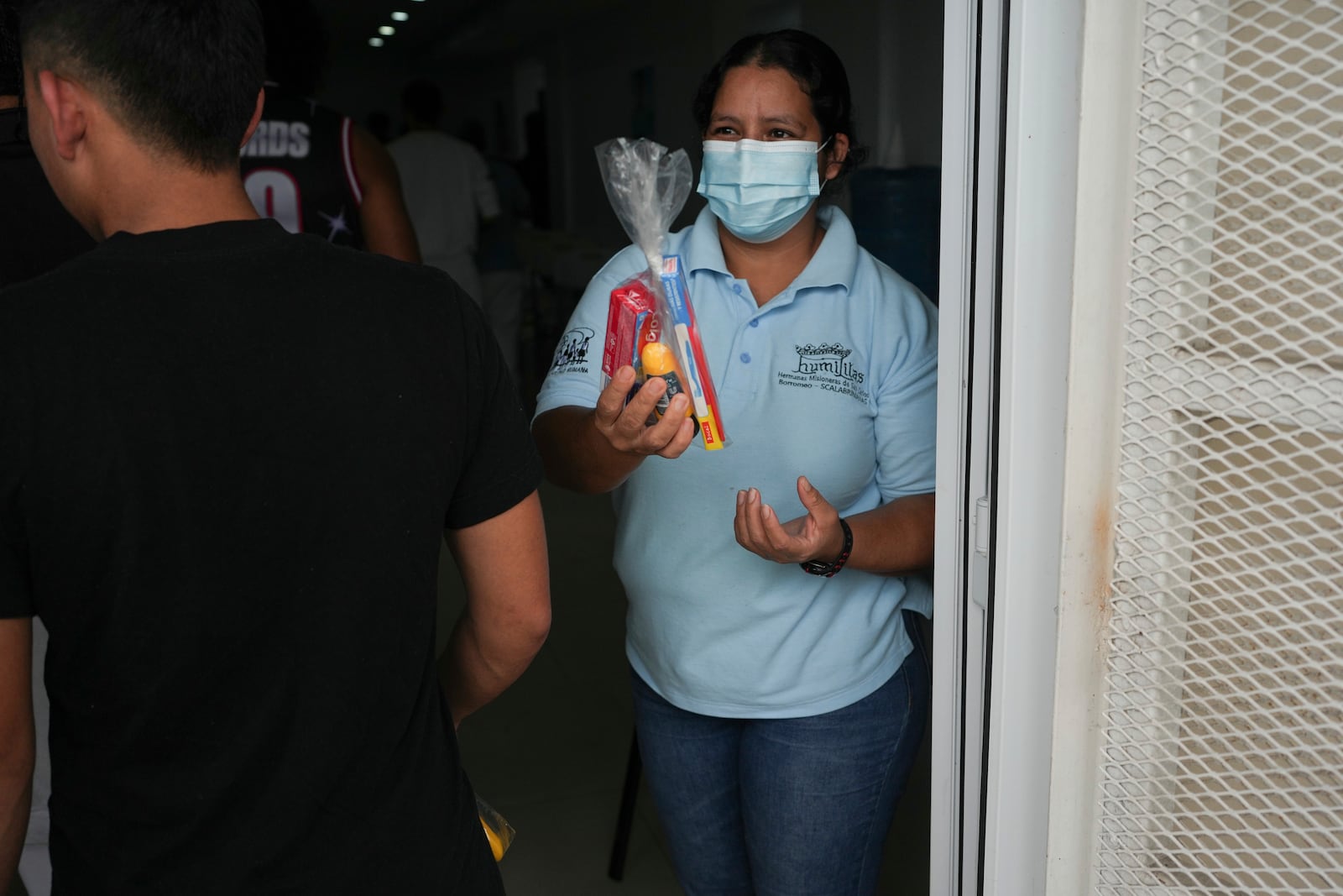 A worker offers personal care kits to Honduran migrants who were deported from the U.S. after they landed at Ramon Villeda Morales Airport in San Pedro Sula, Honduras, Wednesday, Dec. 4, 2024. (AP Photo/Moises Castillo)