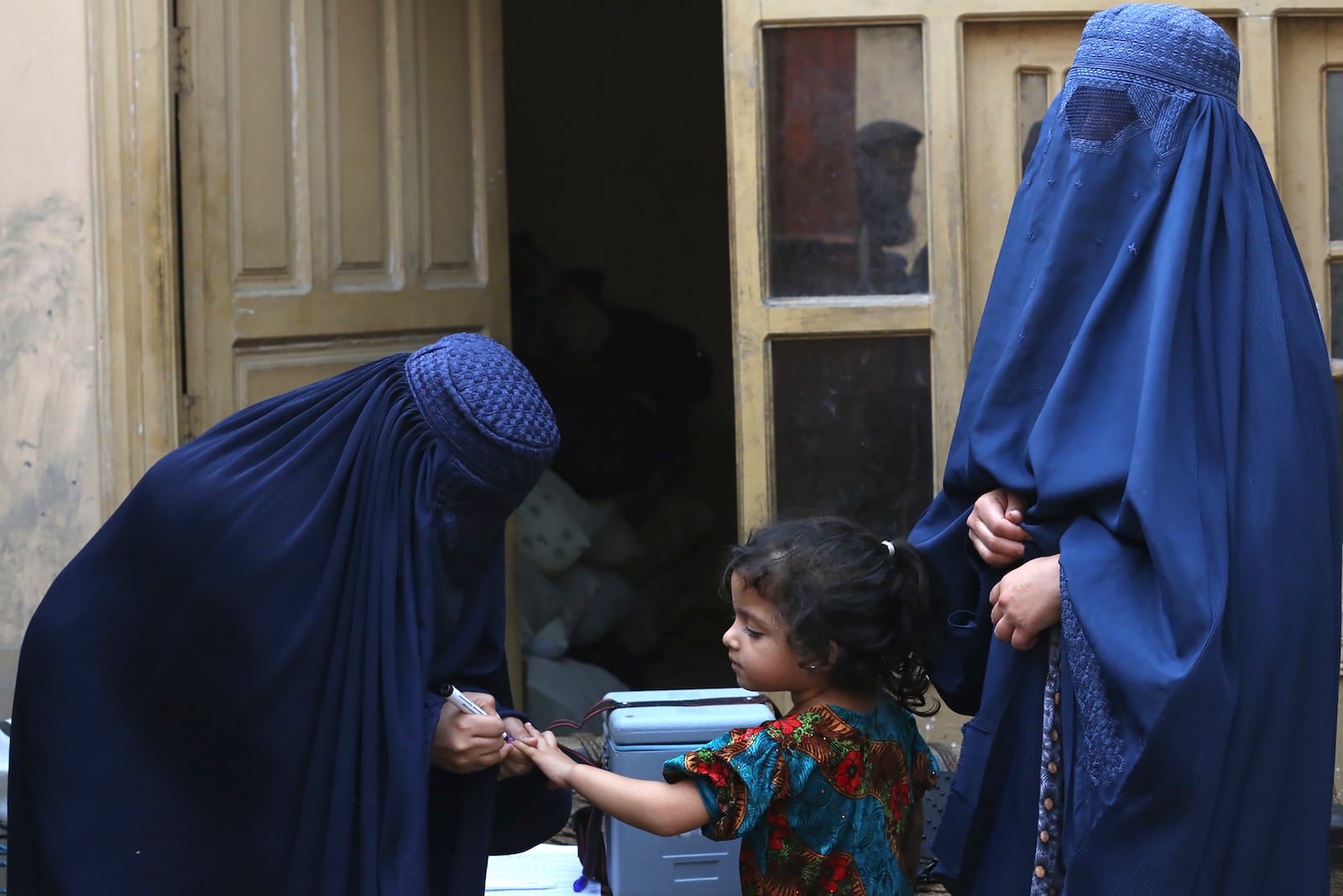 A health worker, left, marks a finger of a child after giving a polio vaccine at a neighborhood of Jalalabad, east of Kabul, Afghanistan, Tuesday, Oct. 29, 2024. (AP Photo/Shafiullah Kakar)