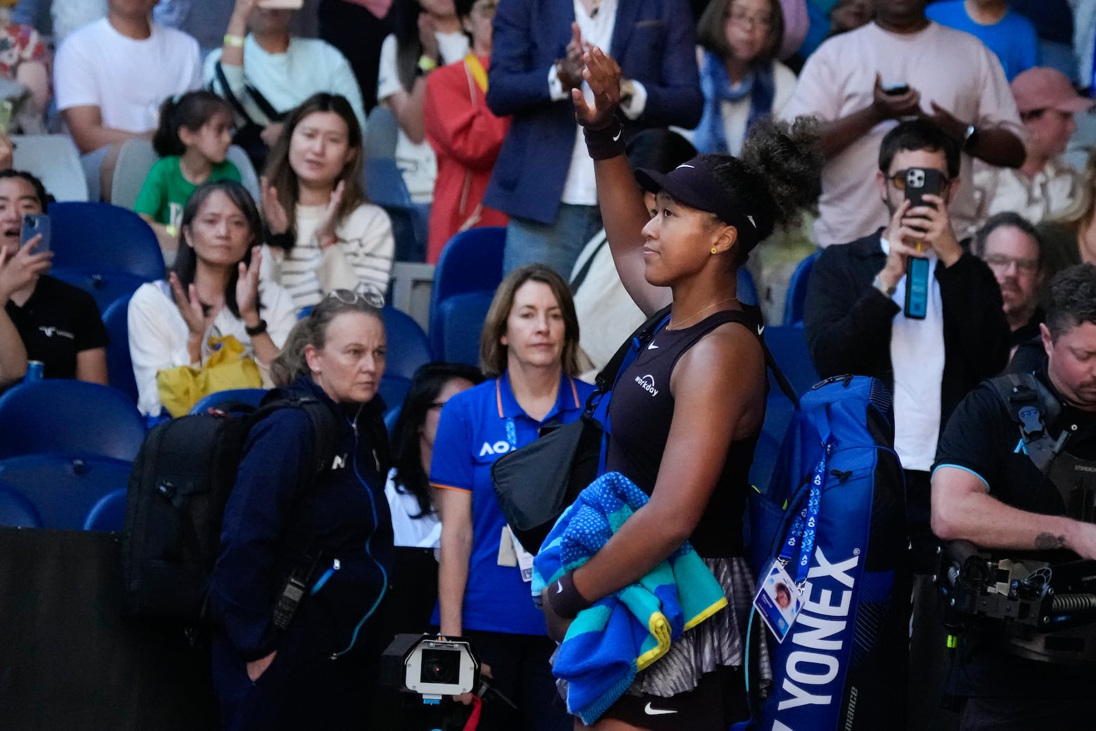 Naomi Osaka of Japan waves as she leaves the court after retiring from her third round match against Belinda Bencic of Switzerland at the Australian Open tennis championship in Melbourne, Australia, Friday, Jan. 17, 2025. (AP Photo/Manish Swarup)