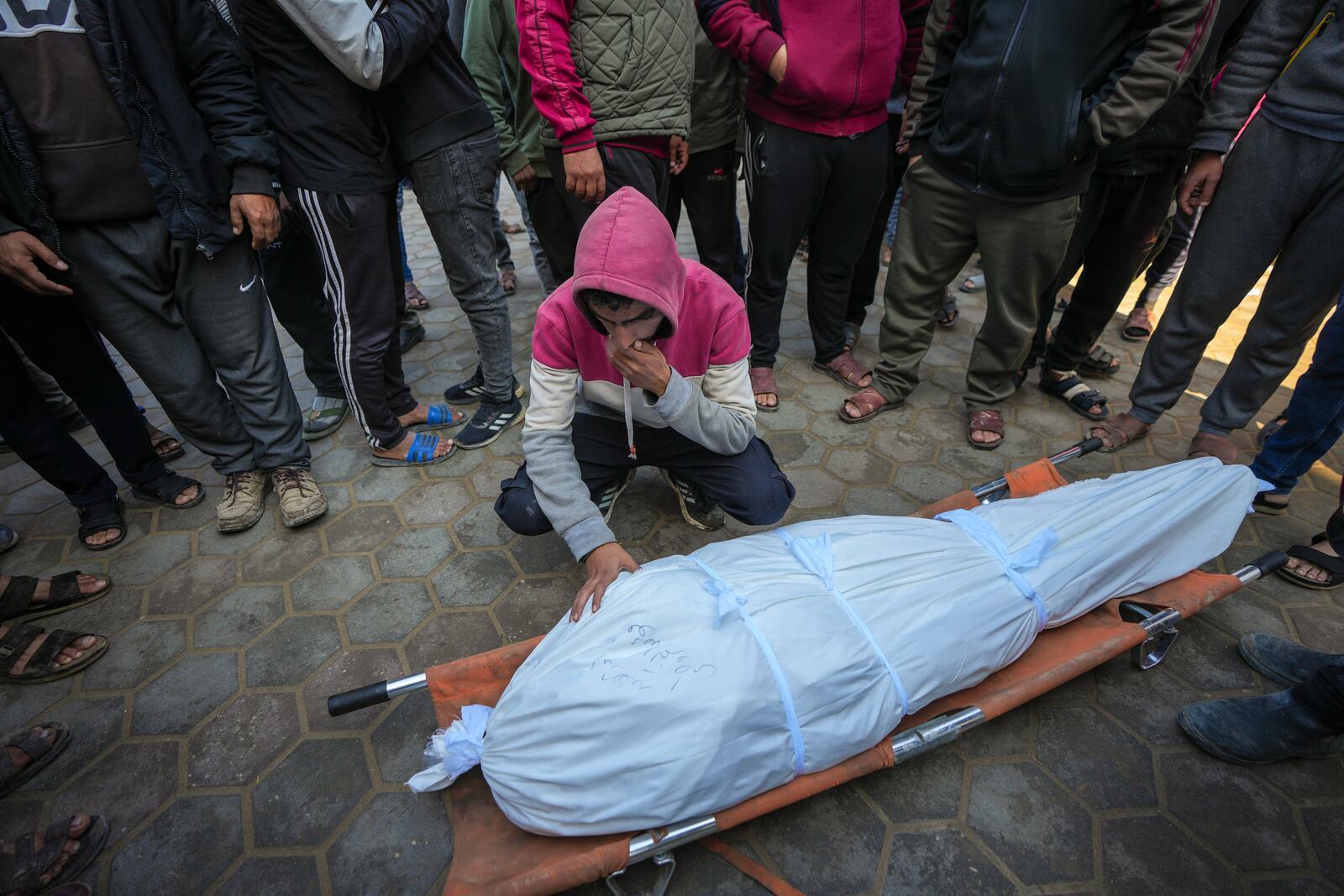 A man mourns over the body of a Palestinian man killed during an Israeli army strike in Deir al-Balah in the central Gaza Strip, Thursday Jan. 2, 2025. The strike killed at least eight men members of local committees that help secure aid convoys, according to the Al-Aqsa Martyrs Hospital, which received the bodies.(AP Photo/Abdel Kareem Hana)