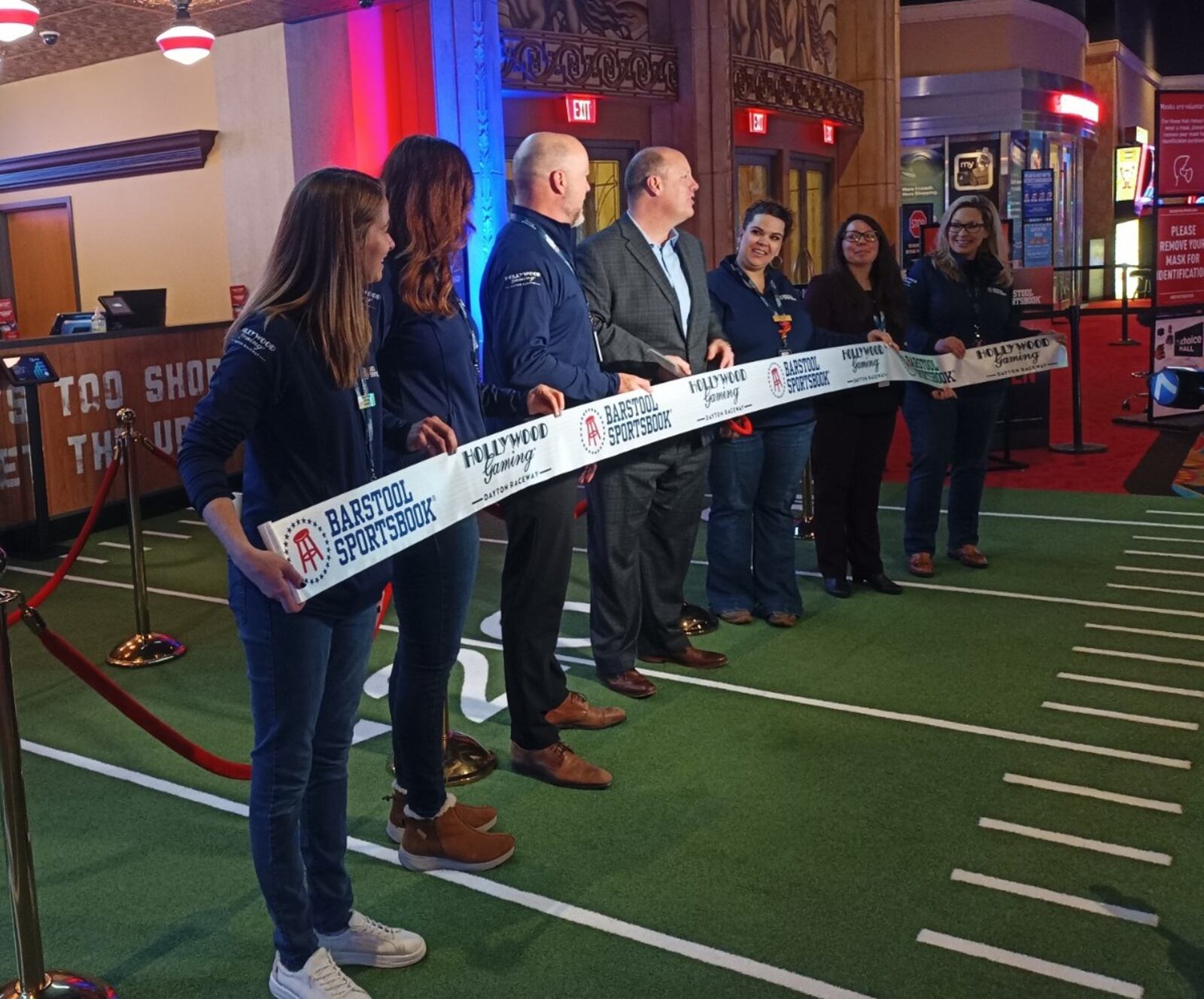 Officials at Hollywood Gaming at Dayton Raceway, including Tim Kelley, vice president and general manager of Hollywood Gaming at Dayton Raceway (center left) and Chris Kershner, president and CEO of the Dayton Area Chamber of Commerce (center right), participate in a ribbon-cutting ceremony on Monday, Jan. 2, 2023, at the racino to commemorate the opening of the Barstool Sportsbook. Additional construction is ongoing at the site, which will include a restaurant, bar, seating area for 130 guests, and 40-foot display for viewing sports. SAMANTHA WILDOW\STAFF