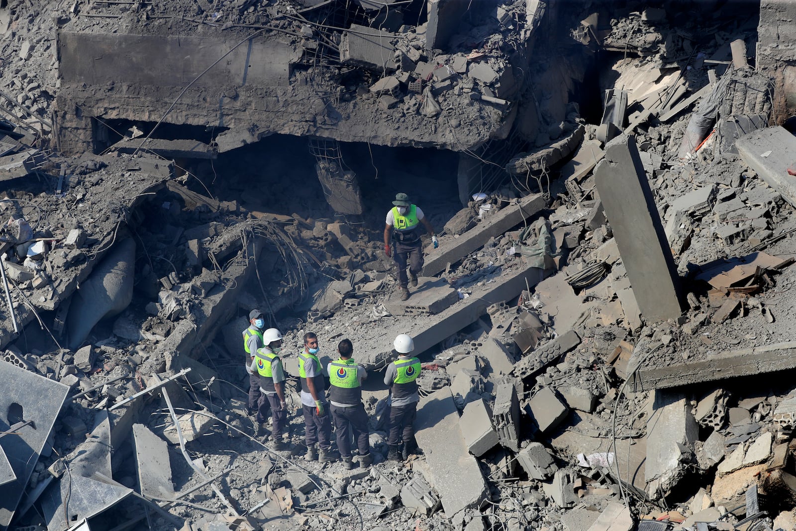 Hezbollah rescue workers stand on the rubble of destroyed buildings at commercial street that was hit Saturday night by Israeli airstrikes, in NAbatiyeh town, south Lebanon, Sunday, Oct. 13, 2024. (AP Photo/Mohammed Zaatari)