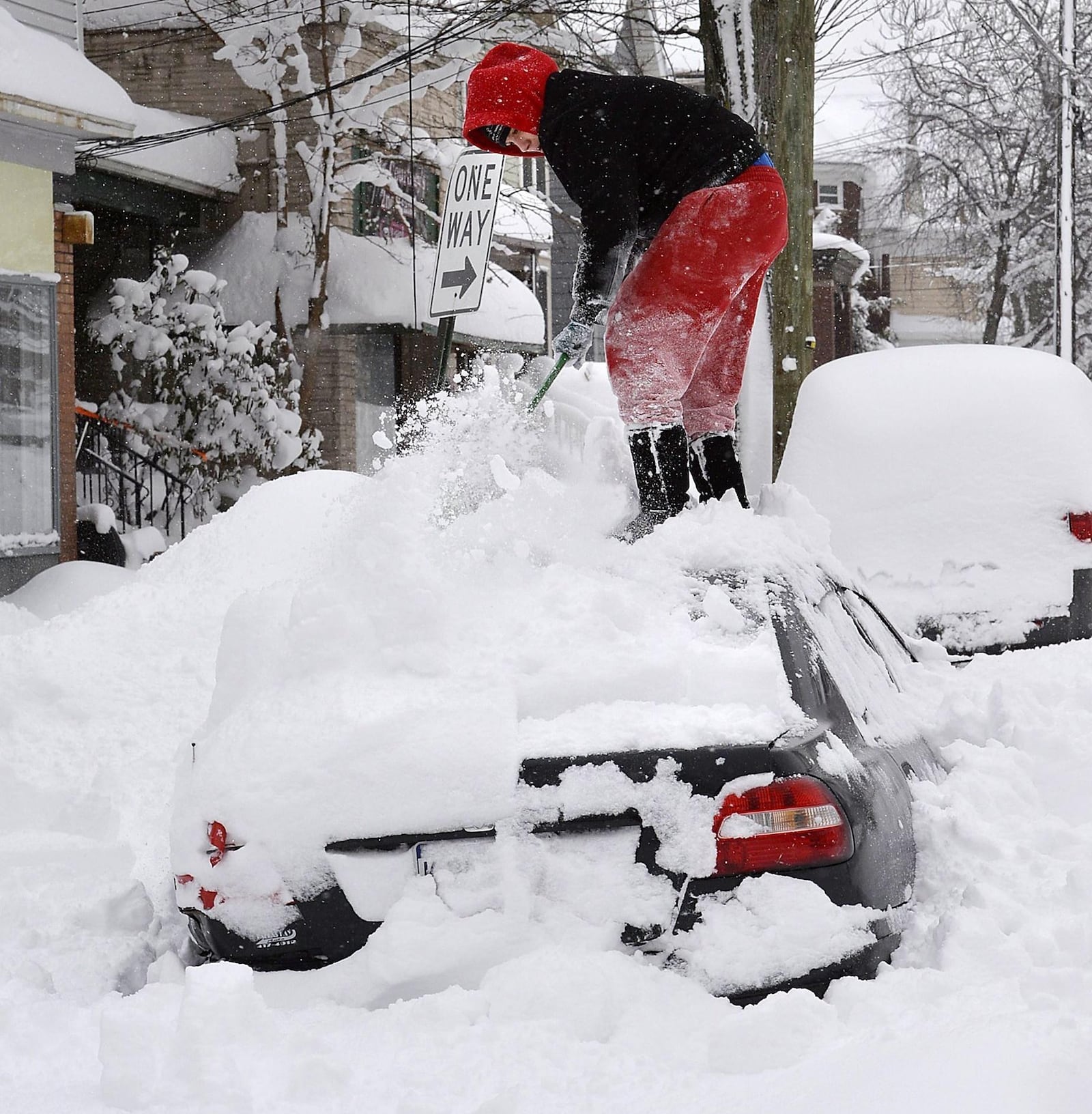 Soledda Hernandez stands on the roof of her car as she brushes off snow in Erie, Pa., Wednesday, Dec. 27, 2017. Snow continues to fall in Erie and surrounding areas that already have seen a record amount of snow over the past few days, prompting a disaster emergency declaration. (Greg Wohlford/Erie Times-News via AP)