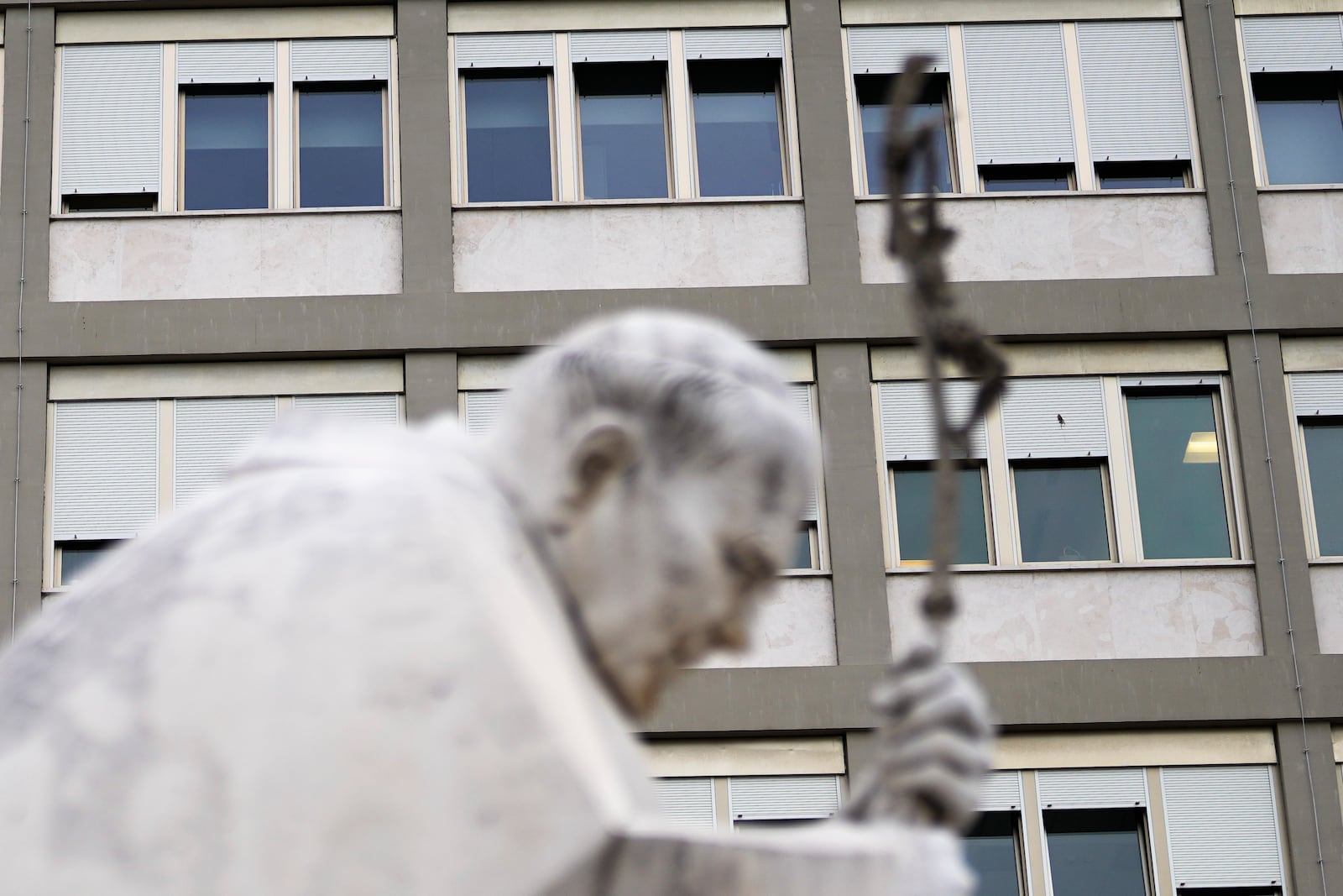 A marble statue of late Pope John Paul II is backdropped by the Agostino Gemelli Polyclinic in Rome, Monday, Feb. 17, 2025, where Pope Francis was hospitalized Friday, Feb. 14, after a weeklong bout of bronchitis worsened and is receiving drug therapy for a respiratory tract infection. (AP Photo/Gregorio Borgia)