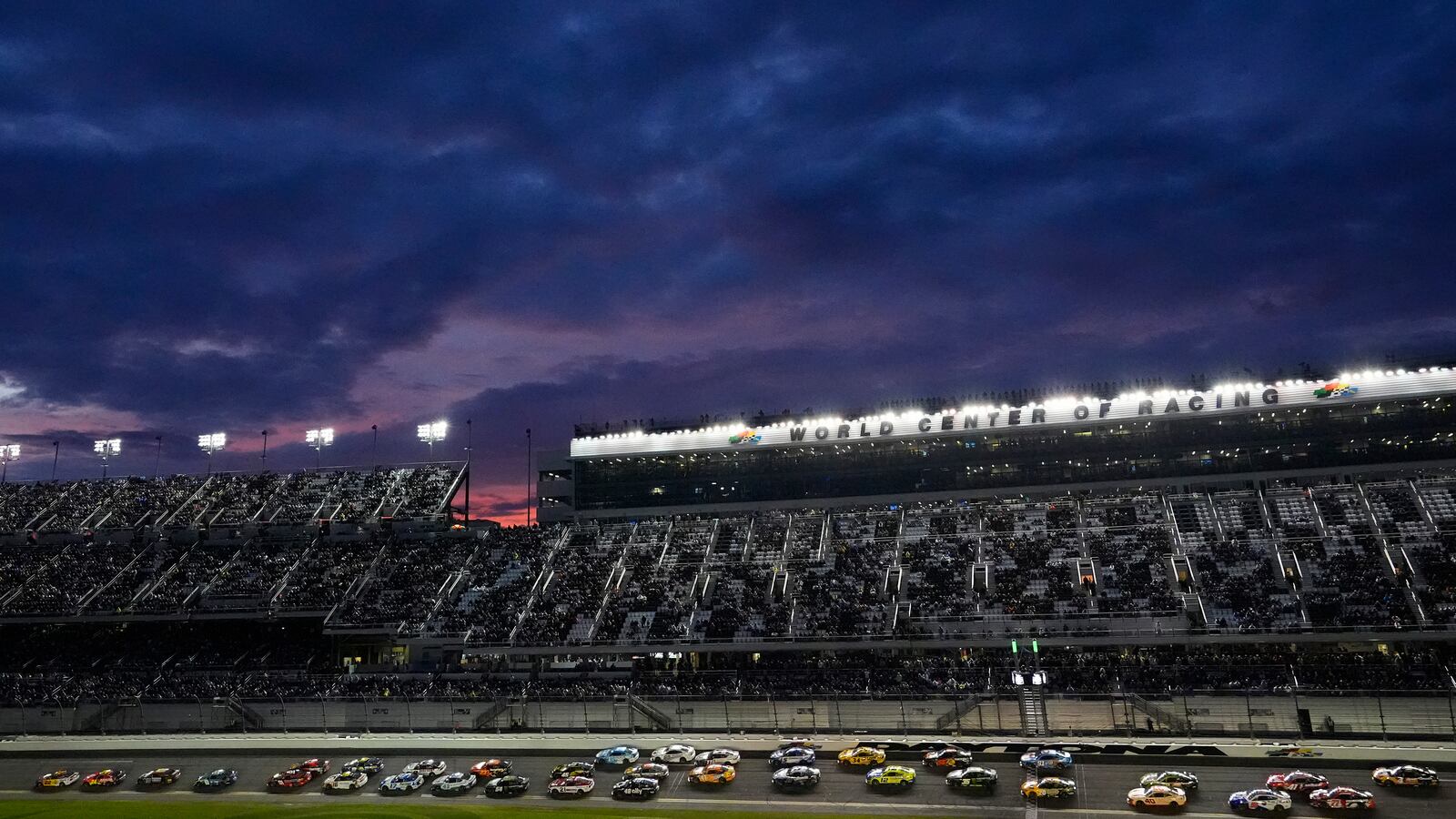 Drivers head into turn one as the sun sets over the grandstand during the NASCAR Daytona 500 auto race Sunday, Feb. 16, 2025, at Daytona International Speedway in Daytona Beach, Fla. (AP Photo/Chris O'Meara)