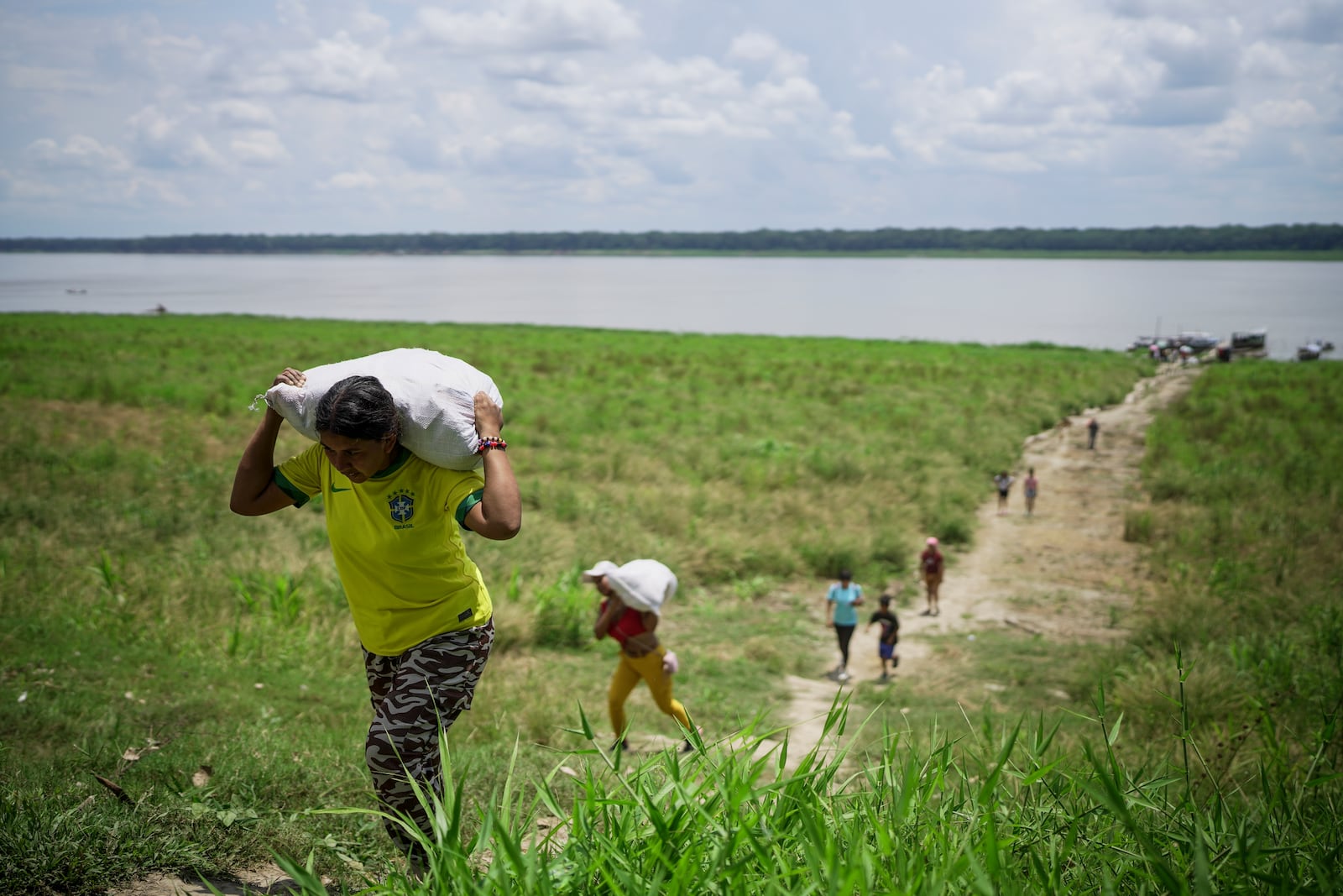 People from the Tikuna Indigenous community carry aid from a nonprofit amid a drought on Amazon River in Loma Linda, near Leticia, Colombia, Sunday, Oct. 20, 2024. (AP Photo/Ivan Valencia)