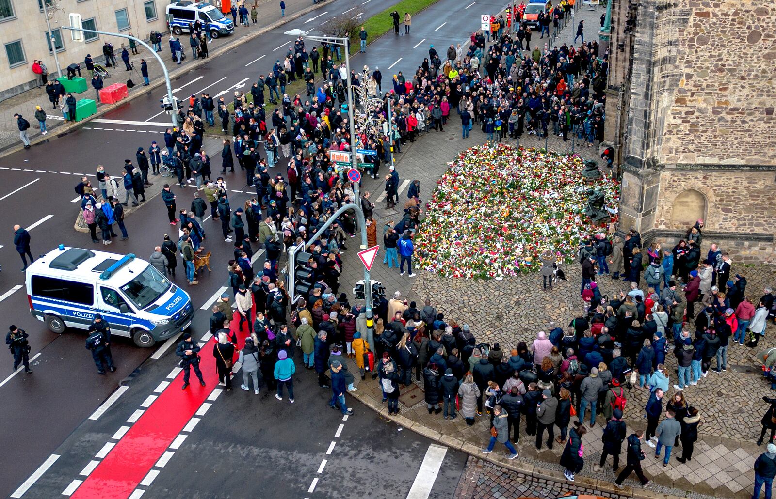 People gather to lay flowers and light candles at the entrance of Johannis church near the Christmas Market, where a car drove into a crowd on Friday evening, in Magdeburg, Germany, Sunday, Dec. 22, 2024. (AP Photo/Michael Probst)