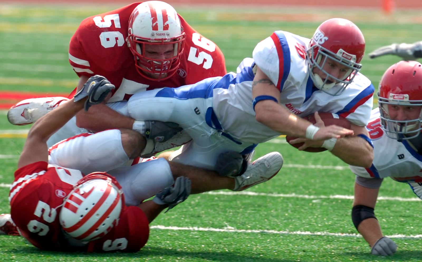 Dayton's Brandon Godsey dives for extra yardage as he's wrapped up by Wittenberg's Mitch Fonseca, bottom, and Lance Phillips during Saturday's game at Wittenberg.  Staff photo by Bill Lackey