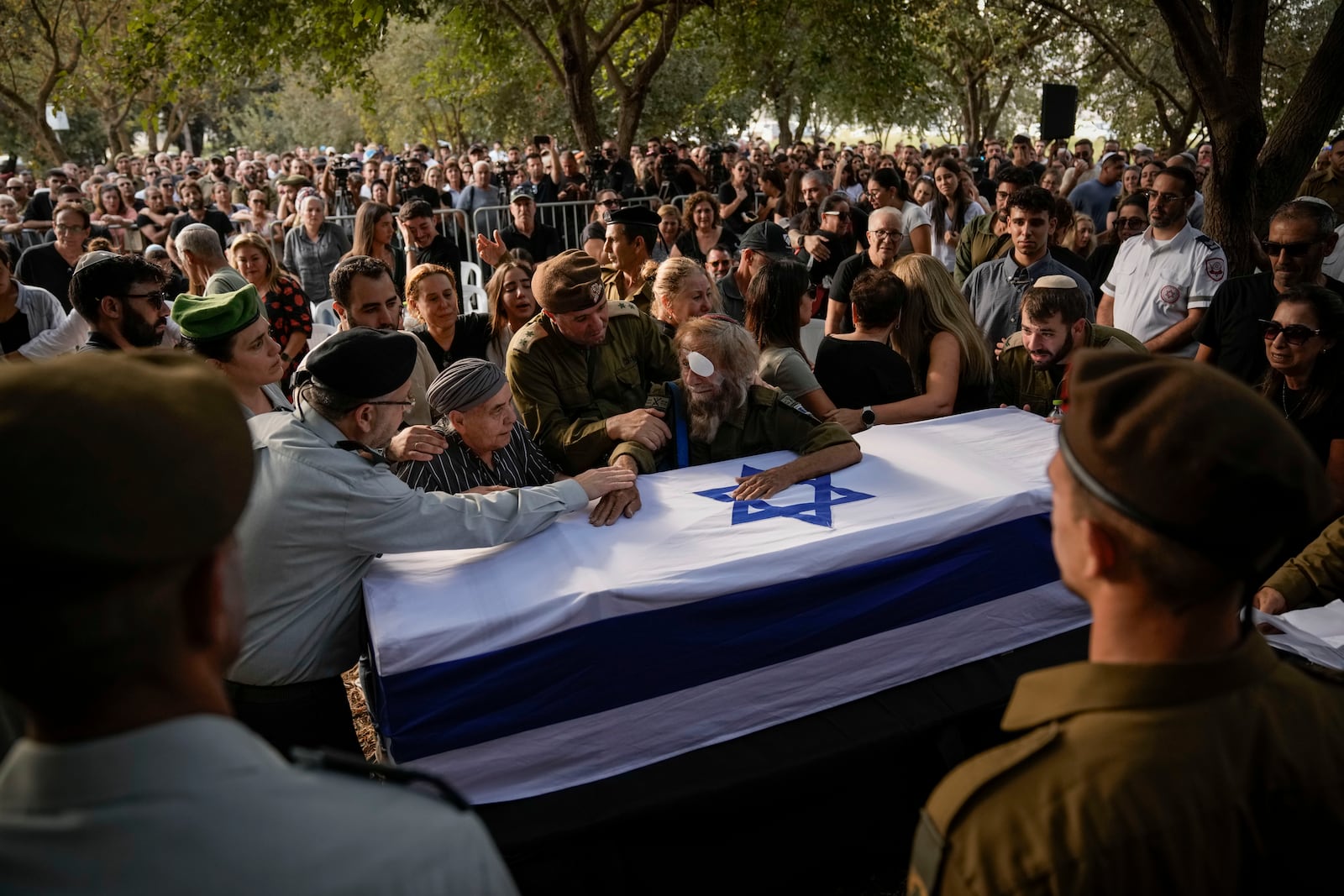 People mourn over the flagged-covered coffin of Israeli soldier Sgt. Amitai Alon, killed by a Hezbollah drone attack, during his funeral near Ramot Naftali, Israel, Monday, Oct. 14, 2024. (AP Photo/Leo Correa)