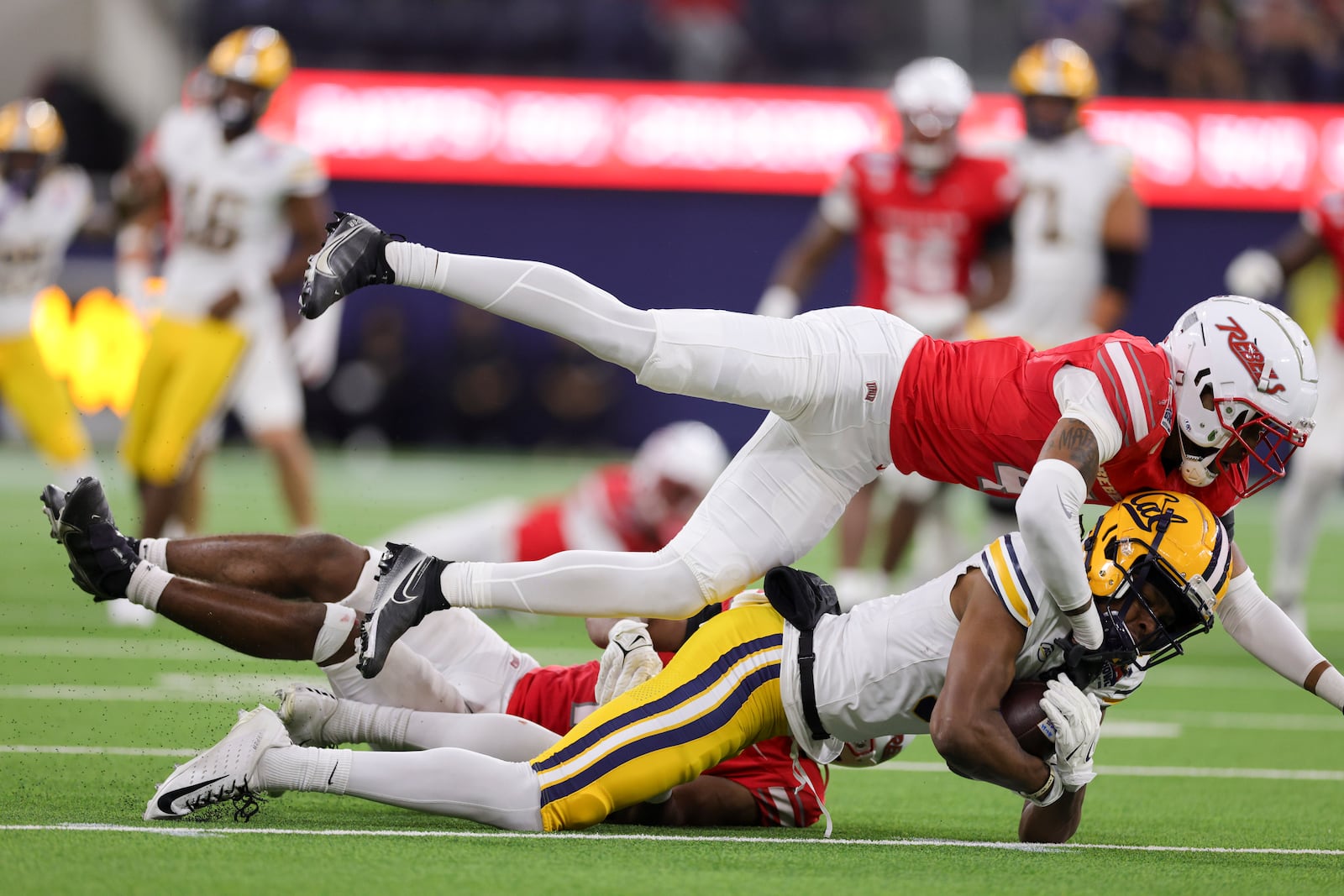 California wide receiver Tobias Merriweather, middle, is tackled by UNLV defensive backs Malik Chavis, top, and Jalen Catalon during the first half of the LA Bowl NCAA college football game Wednesday, Dec. 18, 2024, in Inglewood, Calif. (AP Photo/Ryan Sun)