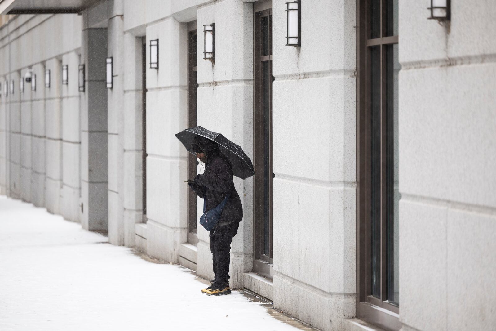 Christopher Brothers holds an umbrella in the snow in Richmond, Va., Wednesday, Feb. 19, 2025. (Mike Kropf/Richmond Times-Dispatch via AP)