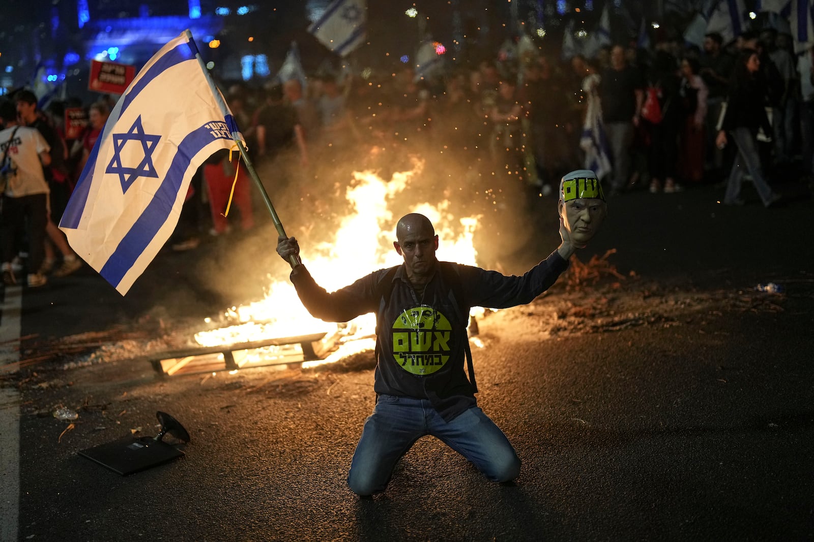 FILE - A protester holds an Israeli flag as Israelis light a bonfire during a protest after Prime Minister Benjamin Netanyahu has dismissed his Defense Minister Yoav Gallant in a surprise announcement in Tel Aviv, Israel, Tuesday, Nov. 5, 2024. (AP Photo/Francisco Seco, File)