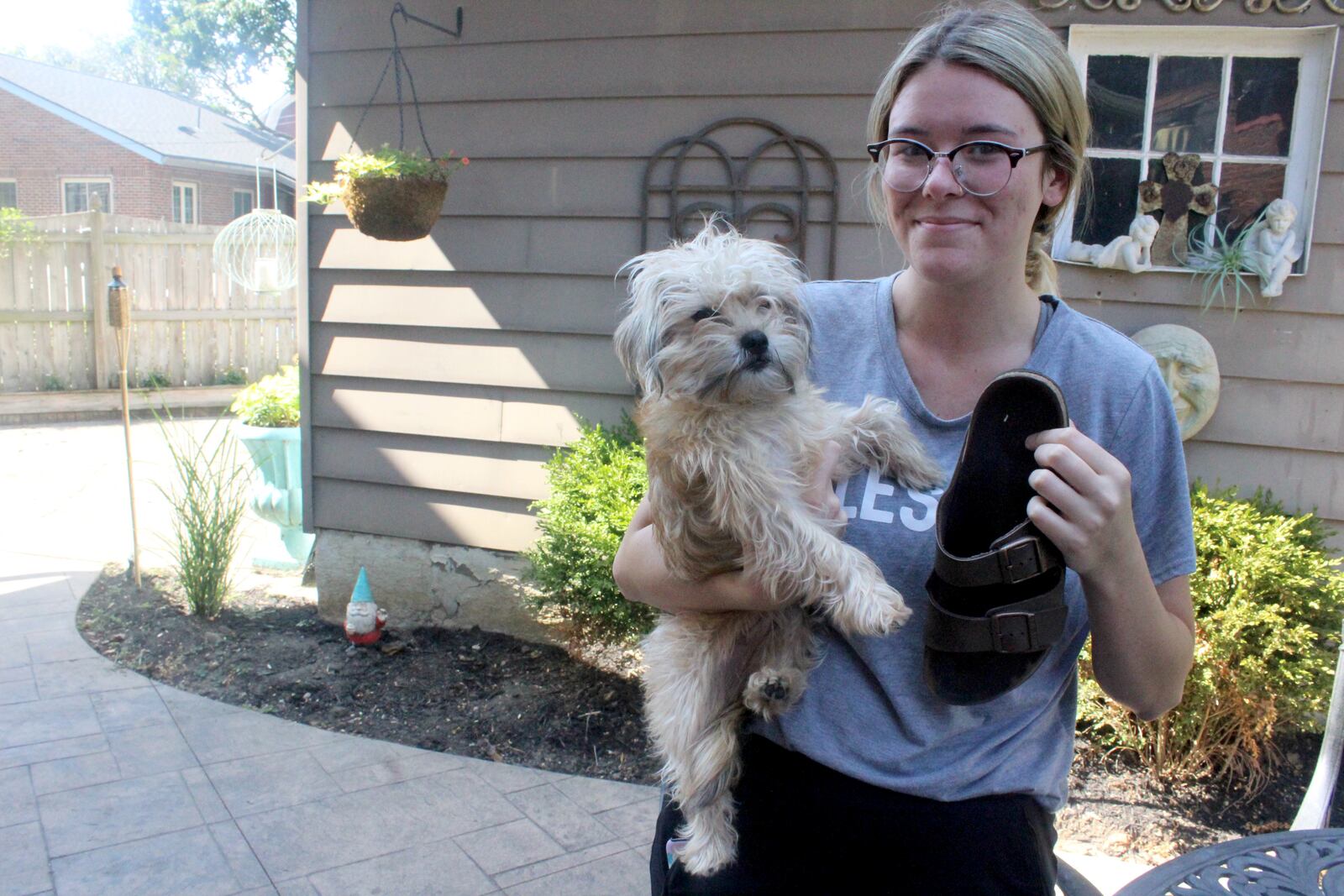 Christina Huelsman with her dog Luda. Huelsman was in Ned Pepper's during the mass shooting in Dayton's Oregon District. She fled the bar, losing the match to the shoe she is holding.