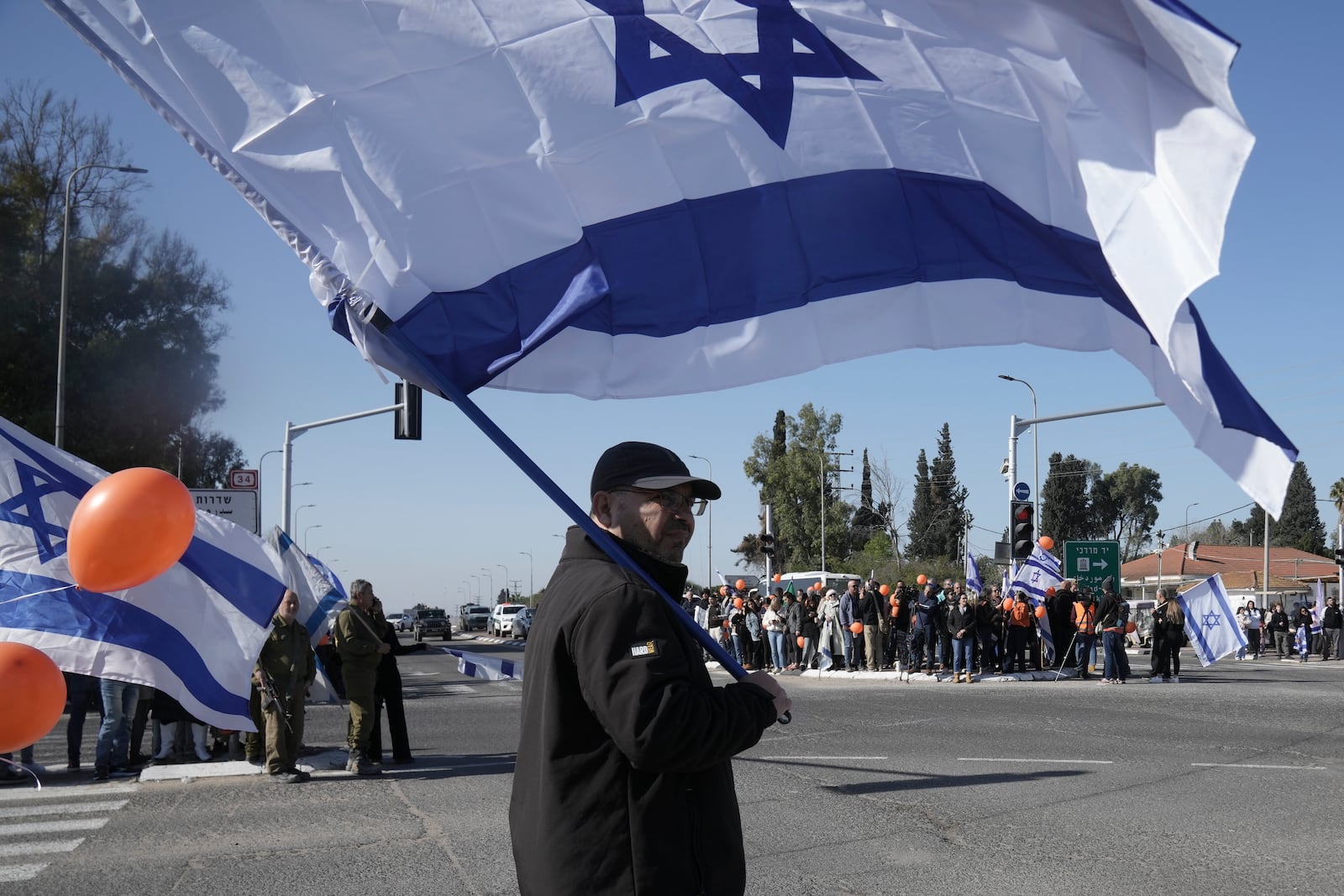 Israelis gather on the side of a road where the funeral convoy carrying the coffins of slain hostages Shiri Bibas and her two children, Ariel and Kfir, will pass by near Kibbutz Yad Mordechai, Israel, Wednesday, Feb. 26, 2025. The mother and her two children were abducted by Hamas on Oct. 7, 2023, and their remains were returned from Gaza to Israel last week as part of a ceasefire agreement with Hamas. (AP Photo/Maya Alleruzzo)