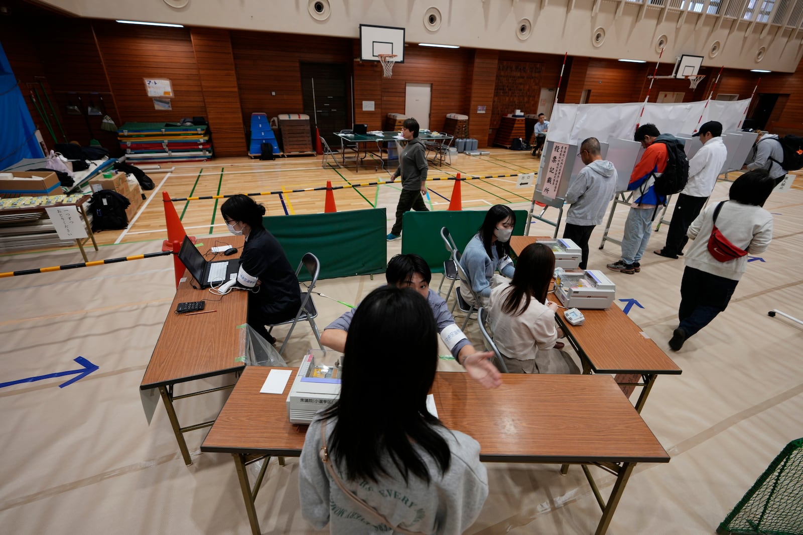 Election staff members help voters at a polling station for Japan's lower house election in Tokyo, Japan, Sunday, Oct. 27, 2024. (AP Photo/Hiro Komae)