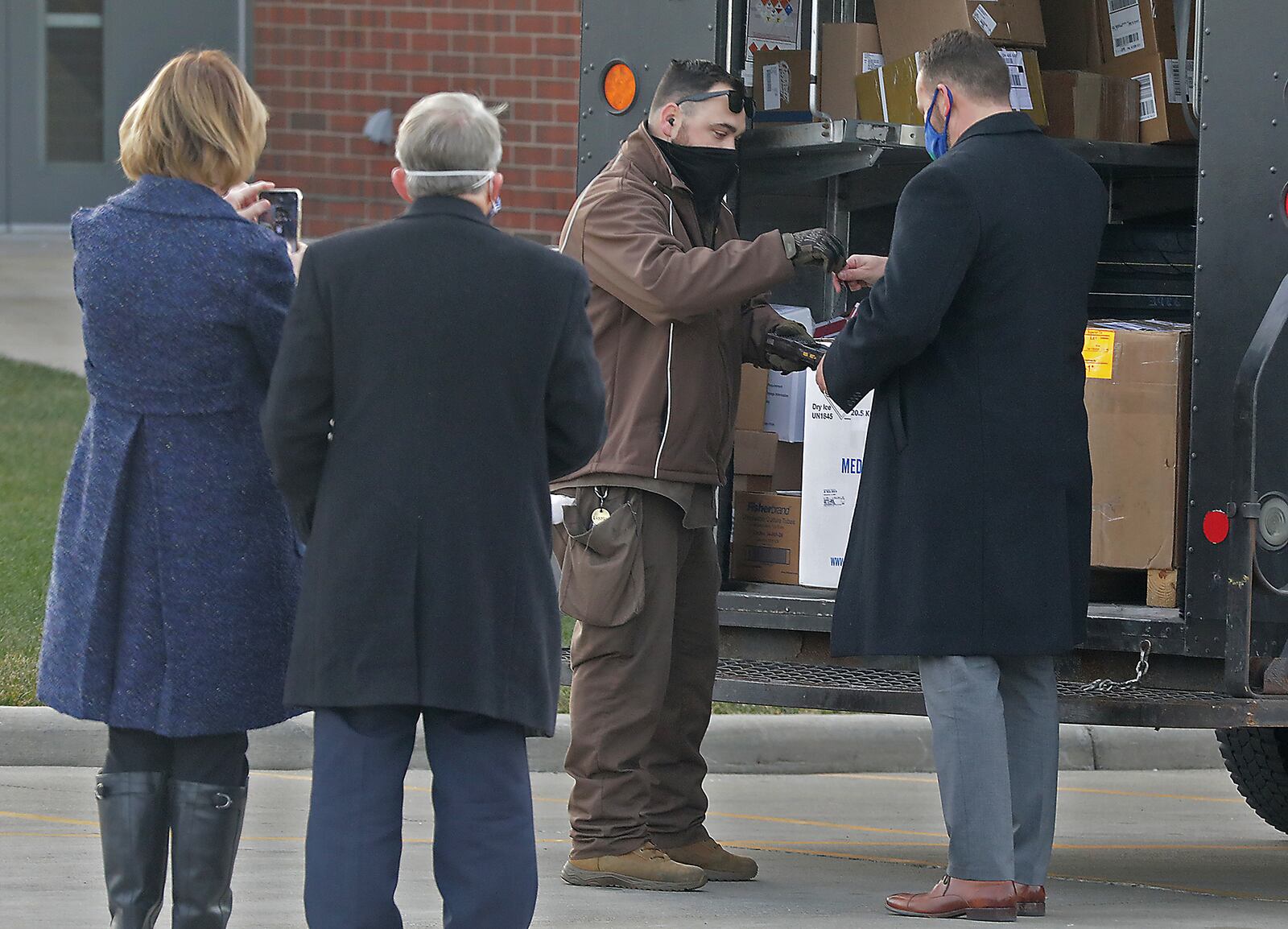 Gov. Mike DeWine and his wife, Fran, watch as Springfield Regional Center President Adam Groshans signs for the UPS delivery of first COVID-19 vaccine arrives at Springfield Regional Medical Center on Dec. 15. BILL LACKEY/STAFF