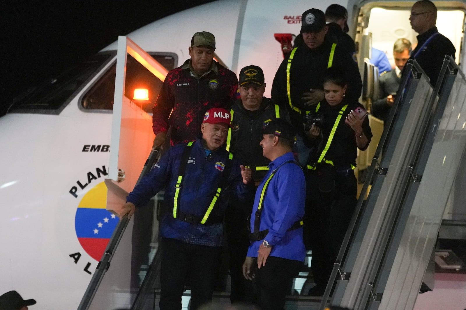 Venezuelan Interior Minister Diosdado Cabello, front left, walks off a plane that transported migrants deported from the United States at Simon Bolivar International Airport in Maiquetia, Venezuela, Monday, Feb. 10, 2025. (AP Photo/Ariana Cubillos)