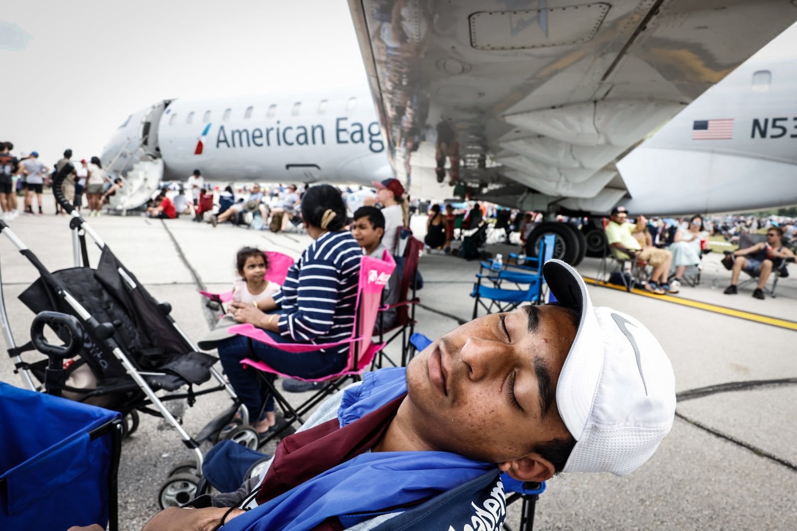 Sandesh N takes a nap under an American Eagle plane at the Dayton Air Show on Saturday. Air temperatures had hit 90 degrees by noon, and the concrete of the Dayton International Airport didn't make it feel any cooler.  Jim Noelker/Staff