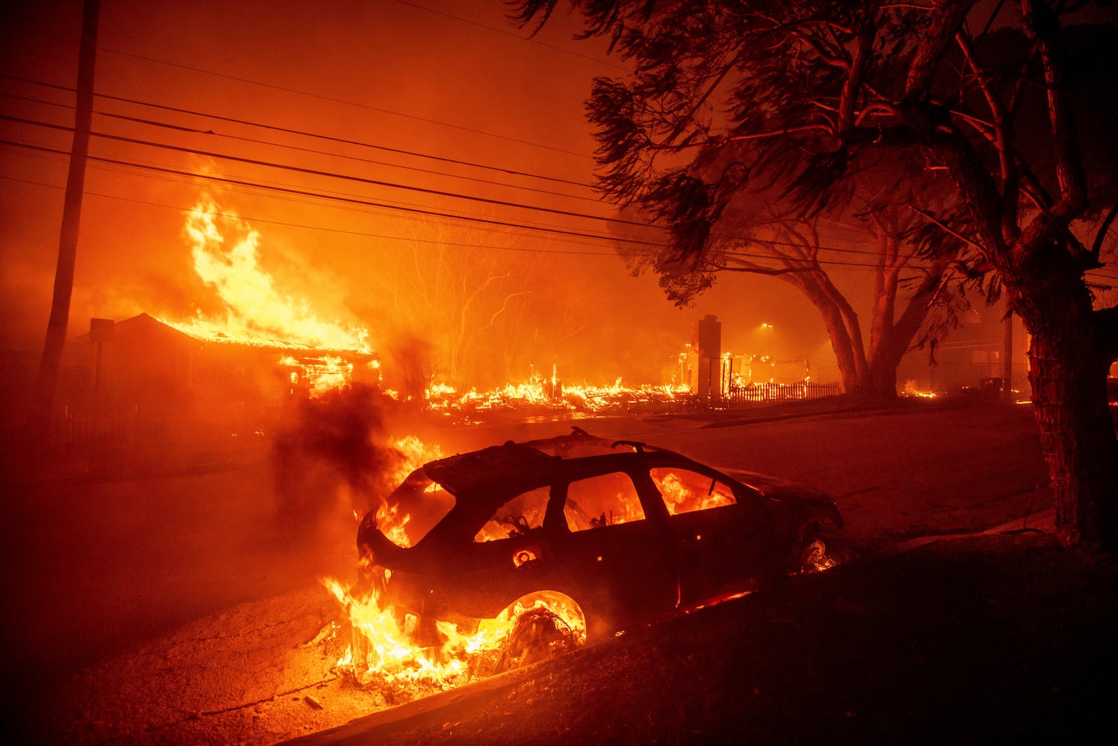 The Palisades Fire burns vehicles and structures in the Pacific Palisades neighborhood of Los Angeles, Tuesday, Jan. 7, 2025. (AP Photo/Ethan Swope)