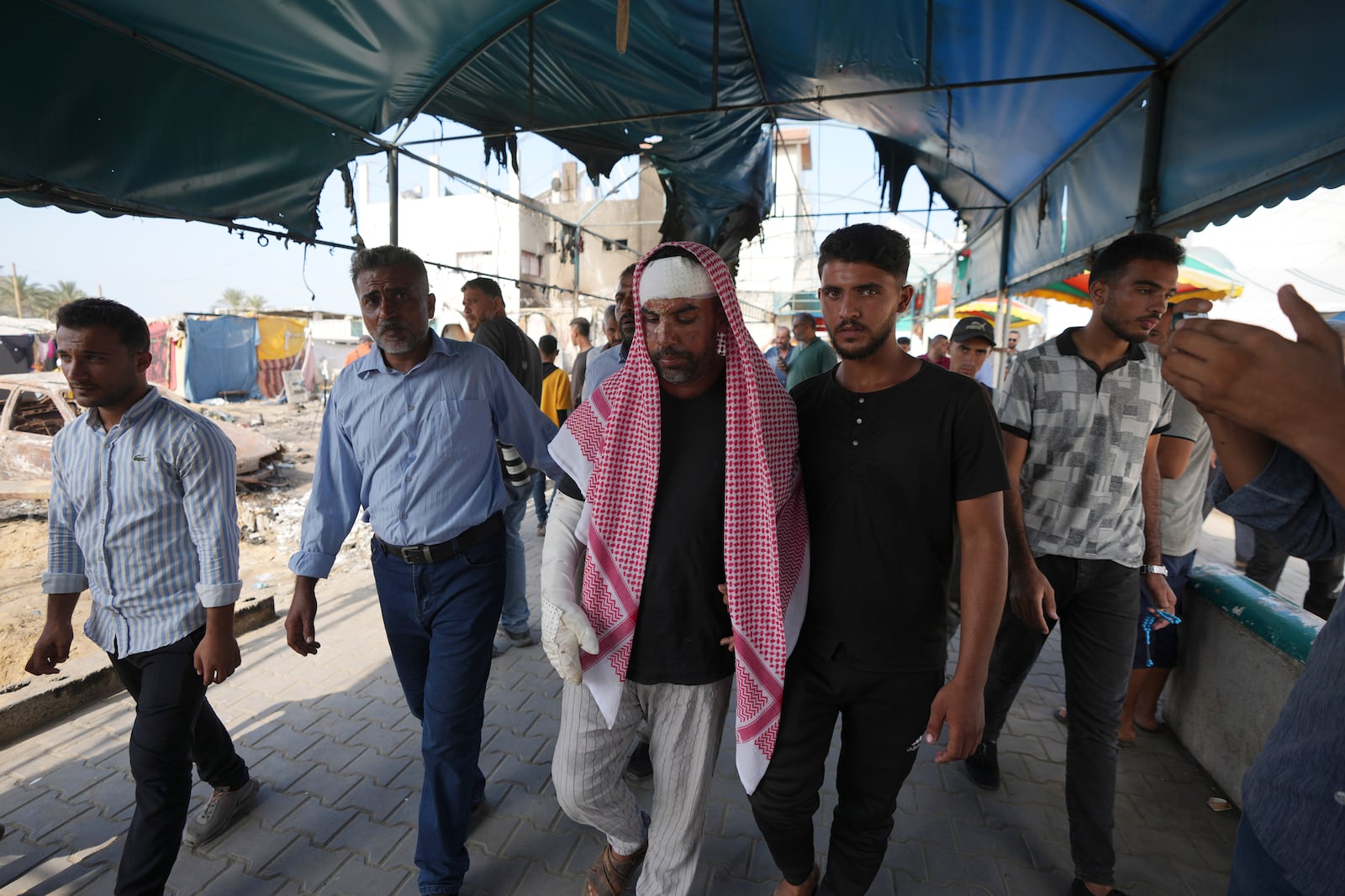 Ahmad al-Dalu, center, whose son, Shaban, was killed in a fire after an Israeli strike hit a tent area in the courtyard of Al Aqsa Martyrs hospital in Deir al-Balah, Gaza Strip, at the site on Wednesday, Oct. 16, 2024. (AP Photo/Abdel Kareem Hana)