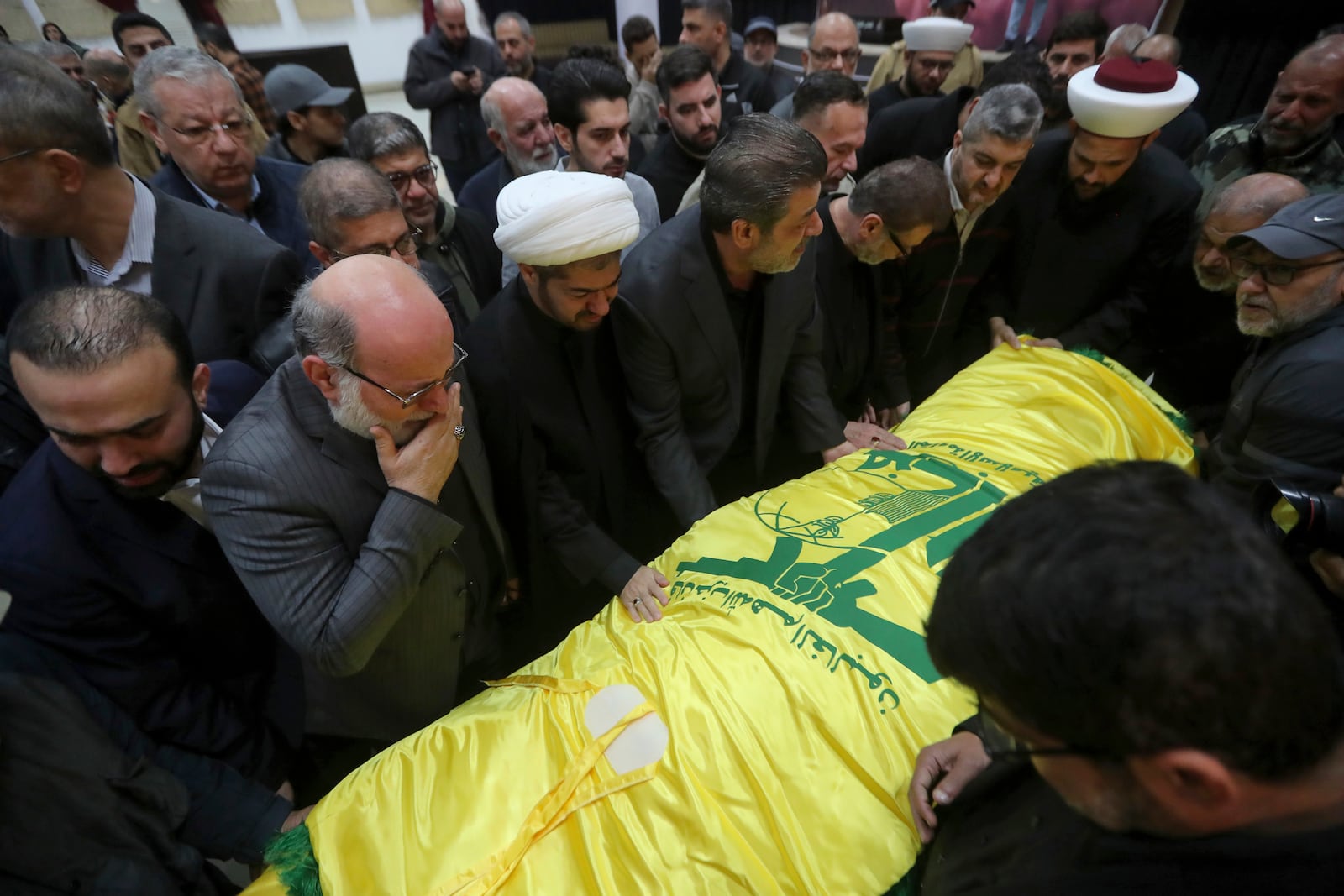 Mourners and relatives of Hezbollah's chief spokesman Mohammed Afif, killed in an Israeli airstrike in Beirut on Sunday, mourn over his body wrapped in a Hezbollah flag, during his funeral in the southern port city of Sidon, Lebanon, Monday, Nov. 18, 2024. (AP Photo/Mohammed Zaatari)