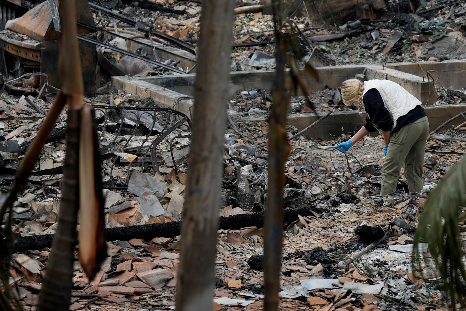 A resident sifts through their fire-damage property after the Franklin Fire swept through, Wednesday, Dec. 11, 2024, in Malibu, Calif. (AP Photo/Damian Dovarganes)