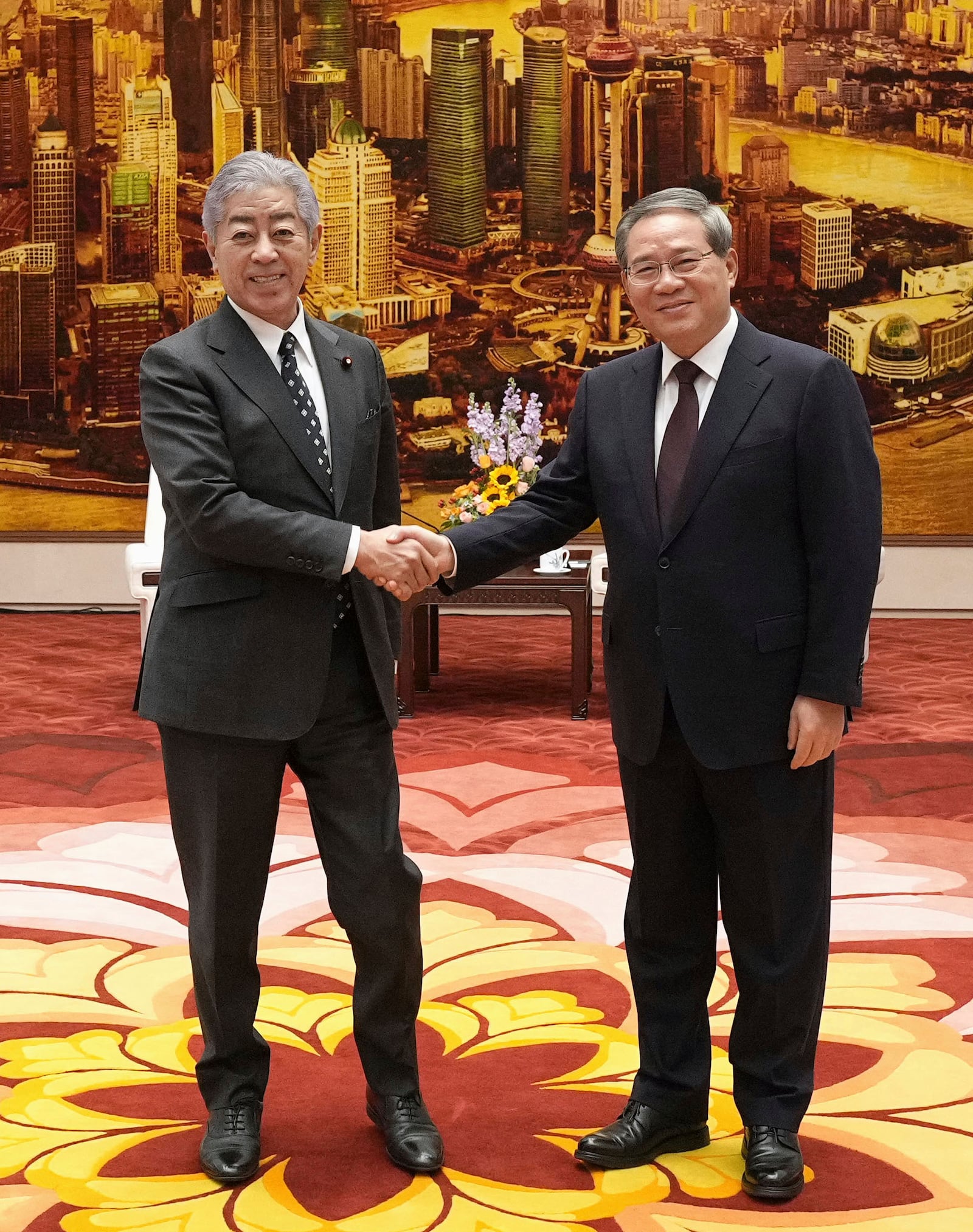 Japan's Foreign Minister Takeshi Iwaya, left, and Chinese Premier Li Qiang, right, shake hands at the Great Hall of the People in Beijing Wednesday, Dec. 25, 2024. (Kyodo News via AP)