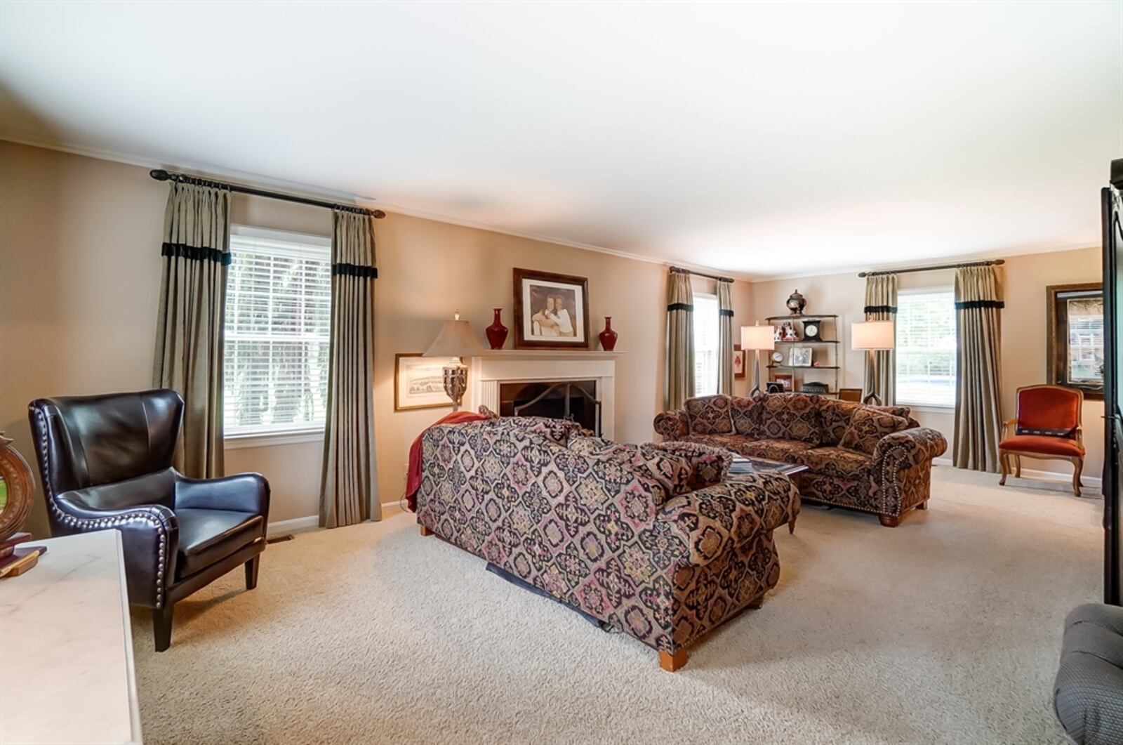 The living room has a fireplace with a fluted wood mantel. Several windows allow for plenty of natural light. 