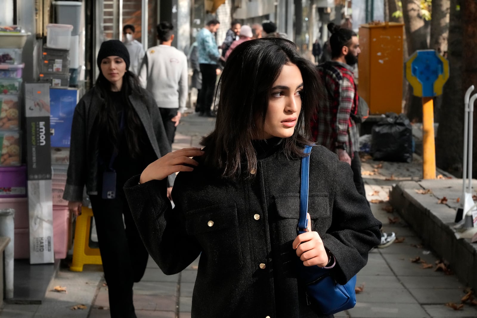 An Iranian woman, without wearing her mandatory Islamic headscarf, walks in northern Tehran, Iran, Friday, Nov. 15, 2024. (AP Photo/Vahid Salemi)