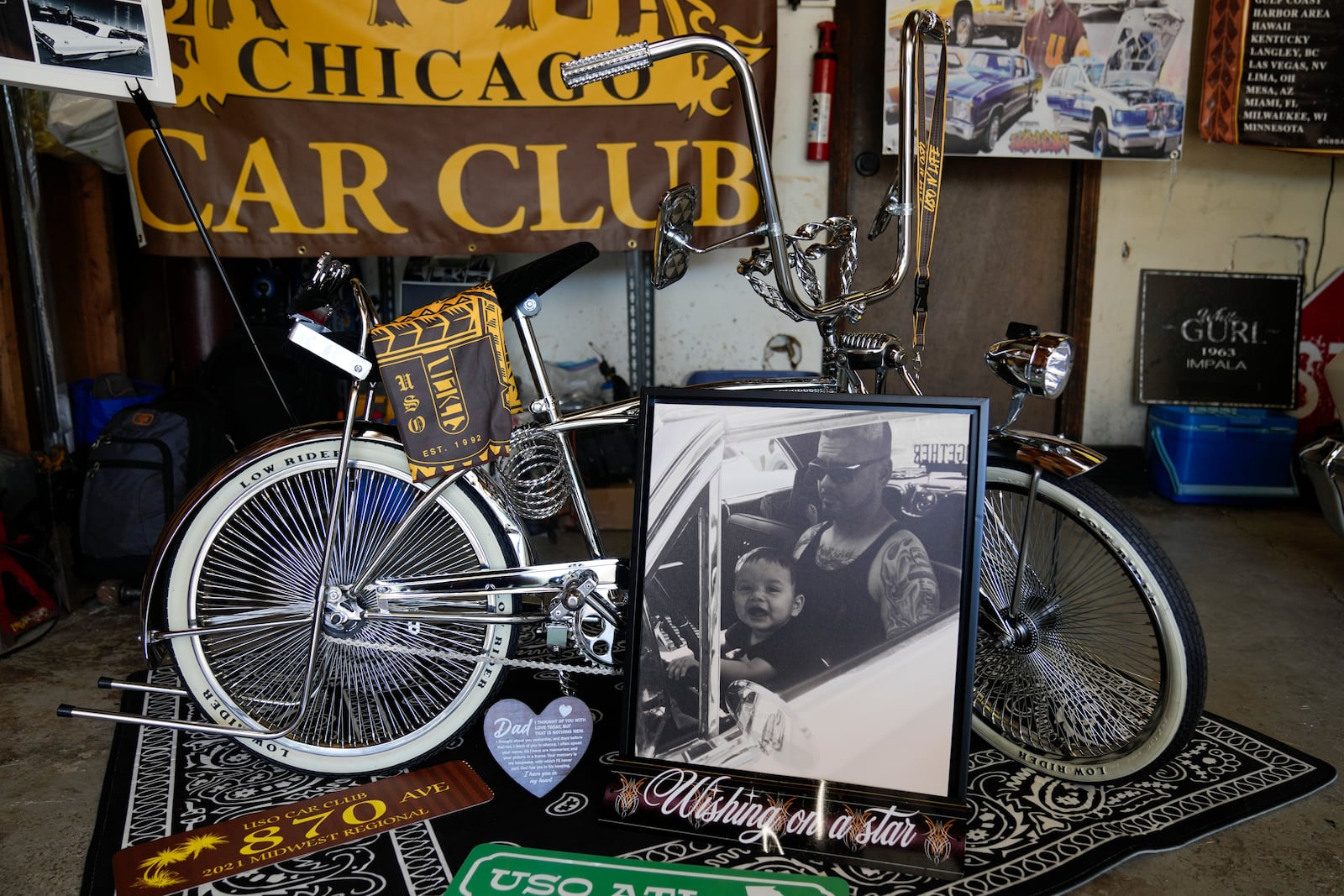 A photo of baby Daniel Marquez, now seven years old, sitting on his late father Alberto's lap inside their 1963 Chevy Impala lowrider car, is displayed with a custom chrome lowrider bike built by Daniel and family friends Saturday, Sept. 14, 2024, at his home in Frankfort, Ill. (AP Photo/Erin Hooley)