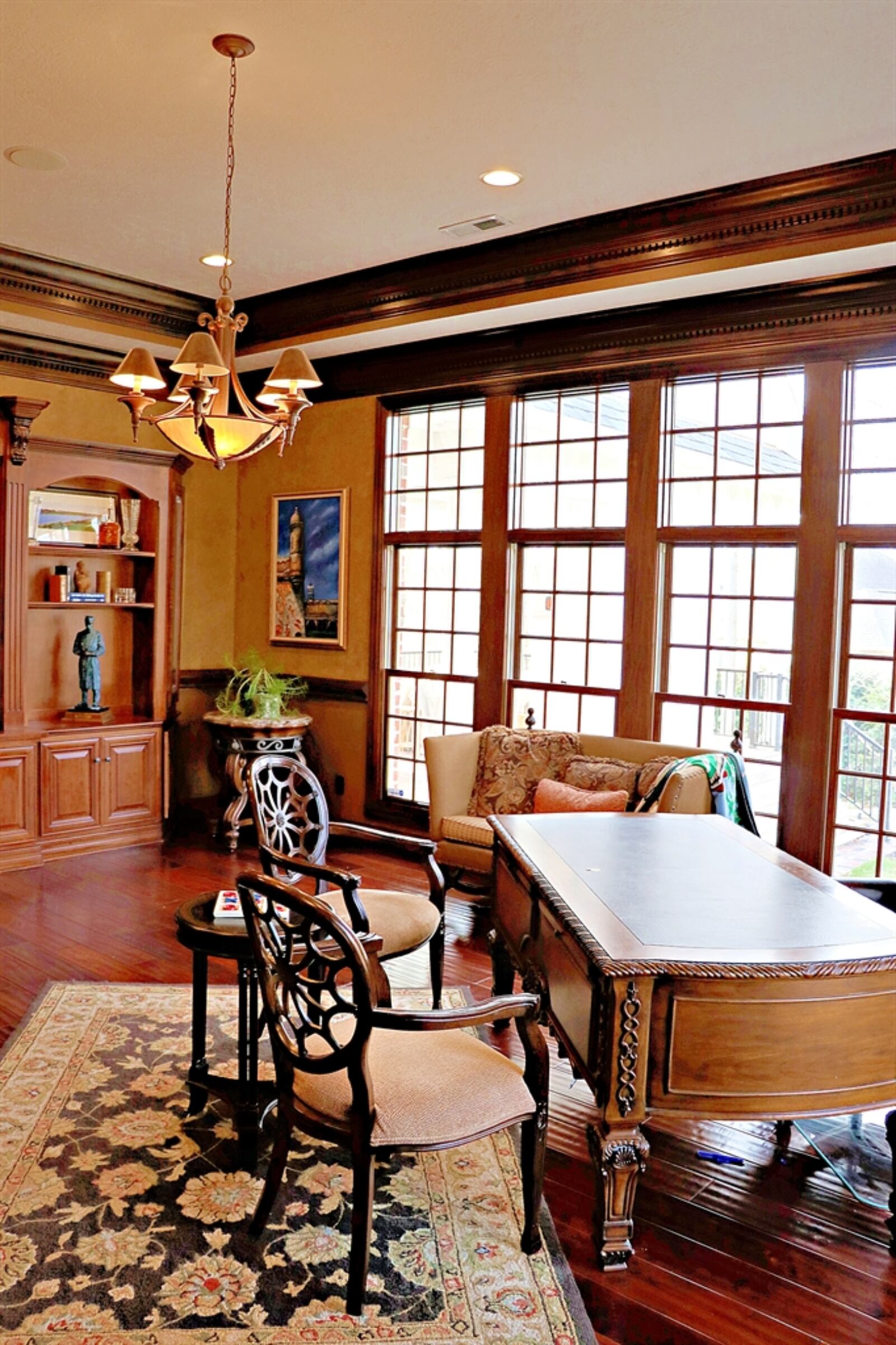 Hand-sawn wood flooring fills the study and complements the three walls of built-in cabinetry — including a media space, open bookcase, granite-counter bar and corner desk hutch. 