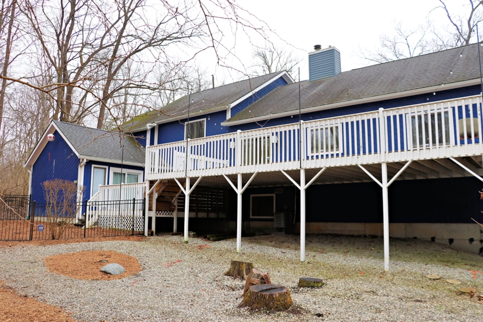 A large multi-level wooden deck stretches across the back of the house and has two sets of steps for backyard access.