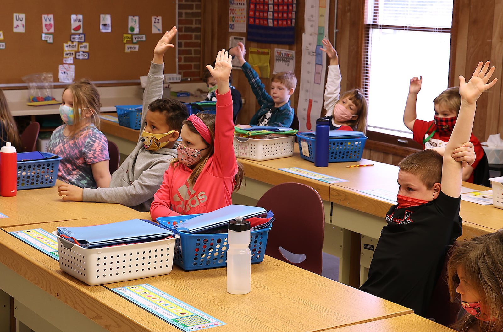 First grade students from Reid School raise their hands to answer a question Monday at The Village. Students and teachers at Reid School had to be relocated to other buildings in the Clark Shawnee School District after Reid became unsafe. BILL LACKEY/STAFF