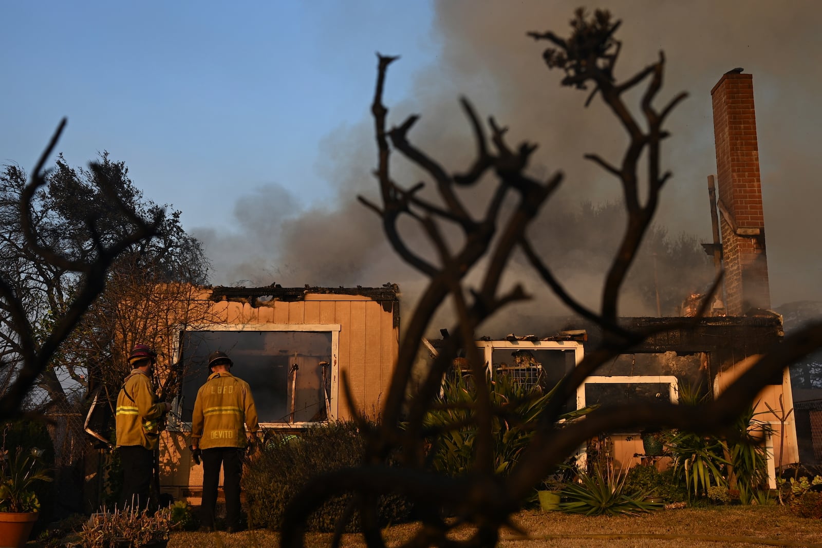 Firefighters look over a home after the Eaton Fire burns in Altadena, Calif., Thursday, Jan. 9, 2025. (AP Photo/Nic Coury)