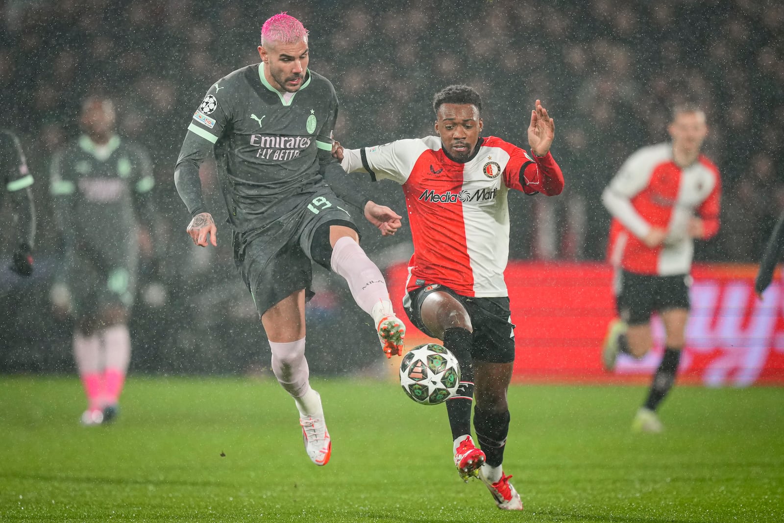 Feyenoord's Antoni Milambo, right, challenges for the ball with AC Milan's Theo Hernandez during the Champions League playoff first leg soccer match between Feyenoord and AC Milan, at the De Kuip stadium, in Rotterdam, Netherlands, Wednesday, Feb. 12, 2025. (AP Photo/Peter Dejong)