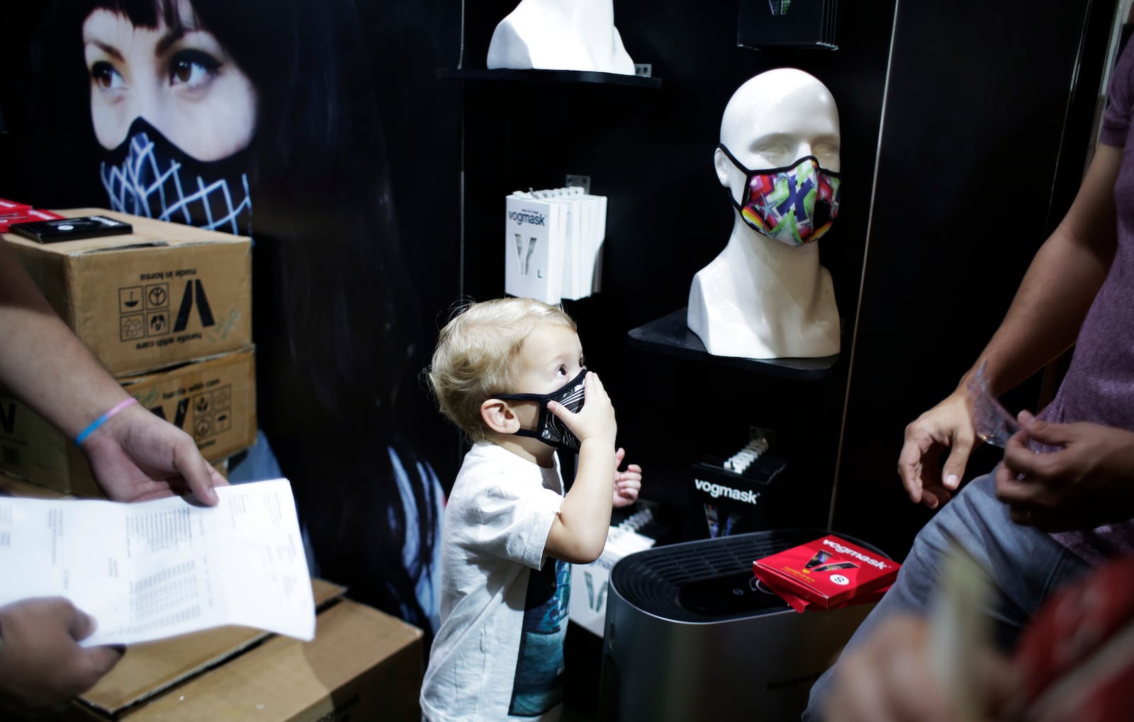 FILE- A child puts on a face mask inside a shop selling masks to fight air pollution in New Delhi, India, on Nov. 4, 2016. (AP Photo/Altaf Qadri, File)