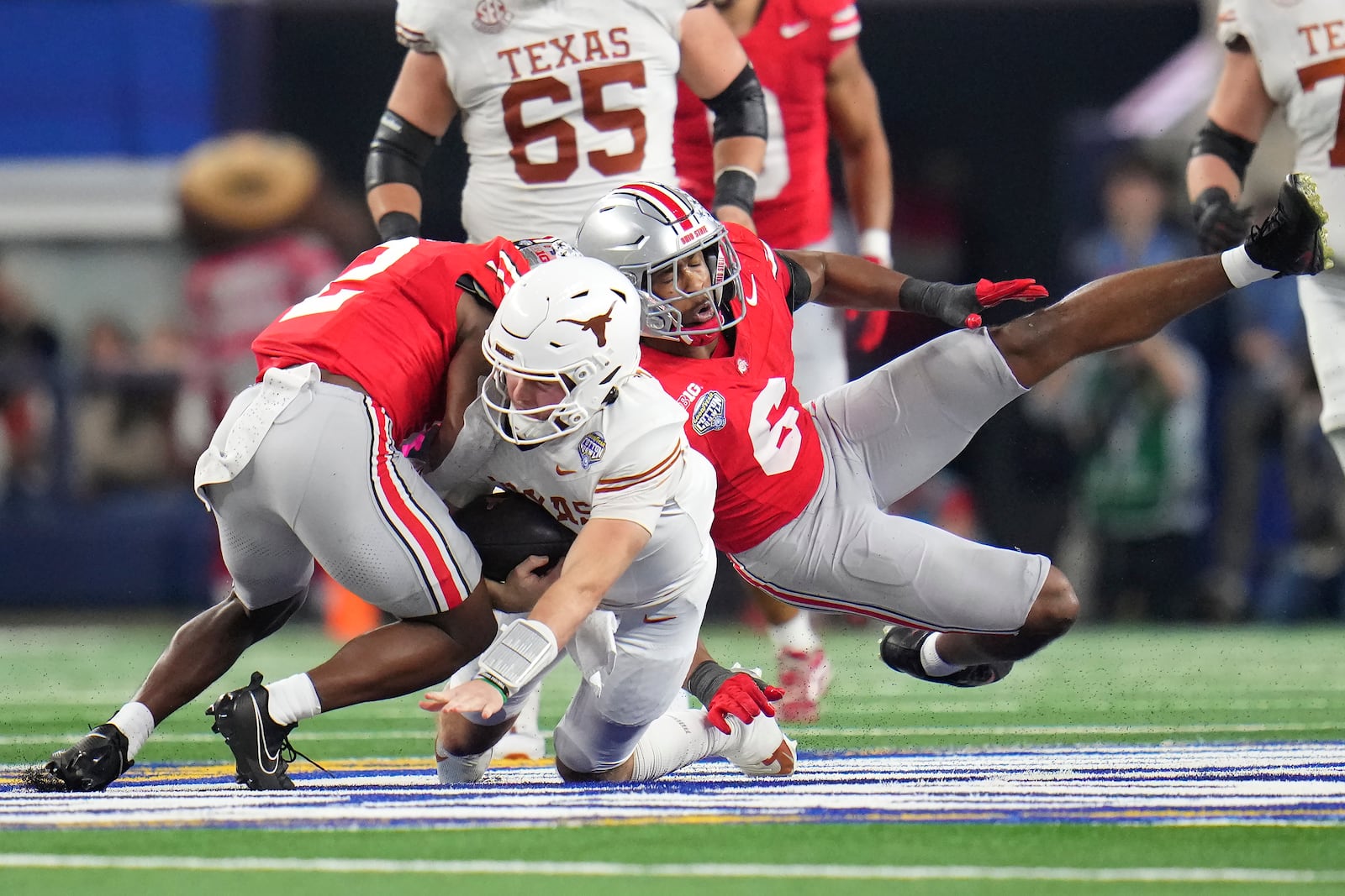 Texas quarterback Quinn Ewers, middle, runs against Ohio State safety Caleb Downs, left, and safety Sonny Styles (6) during the first half of the Cotton Bowl College Football Playoff semifinal game, Friday, Jan. 10, 2025, in Arlington, Texas. (AP Photo/Julio Cortez)