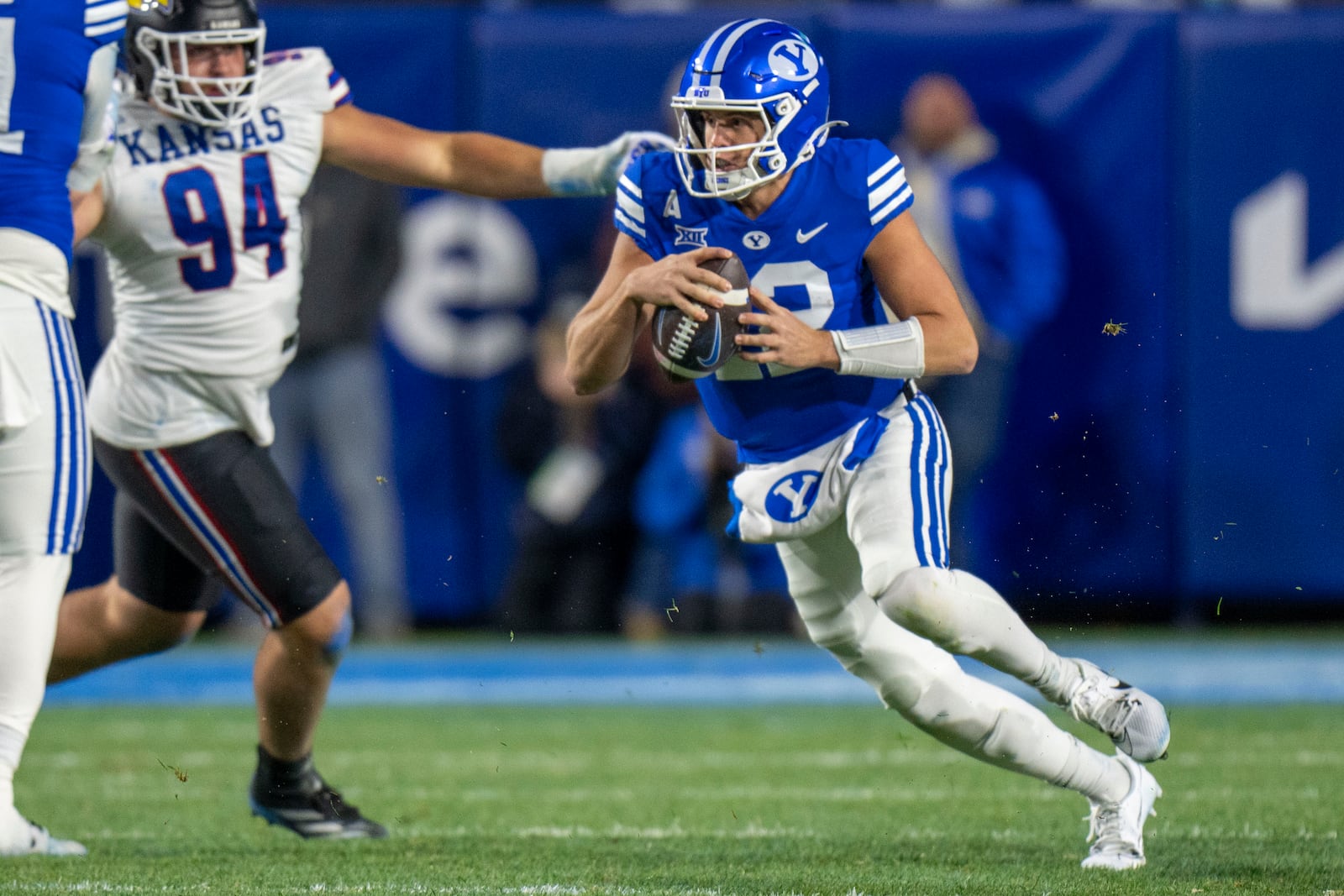 BYU quarterback Jake Retzlaff (12) runs the ball, as Kansas defensive tackle Blake Herold (94) defends during the first half of an NCAA college football game, Saturday, Nov. 16, 2024, in Provo. (AP Photo/Rick Egan)