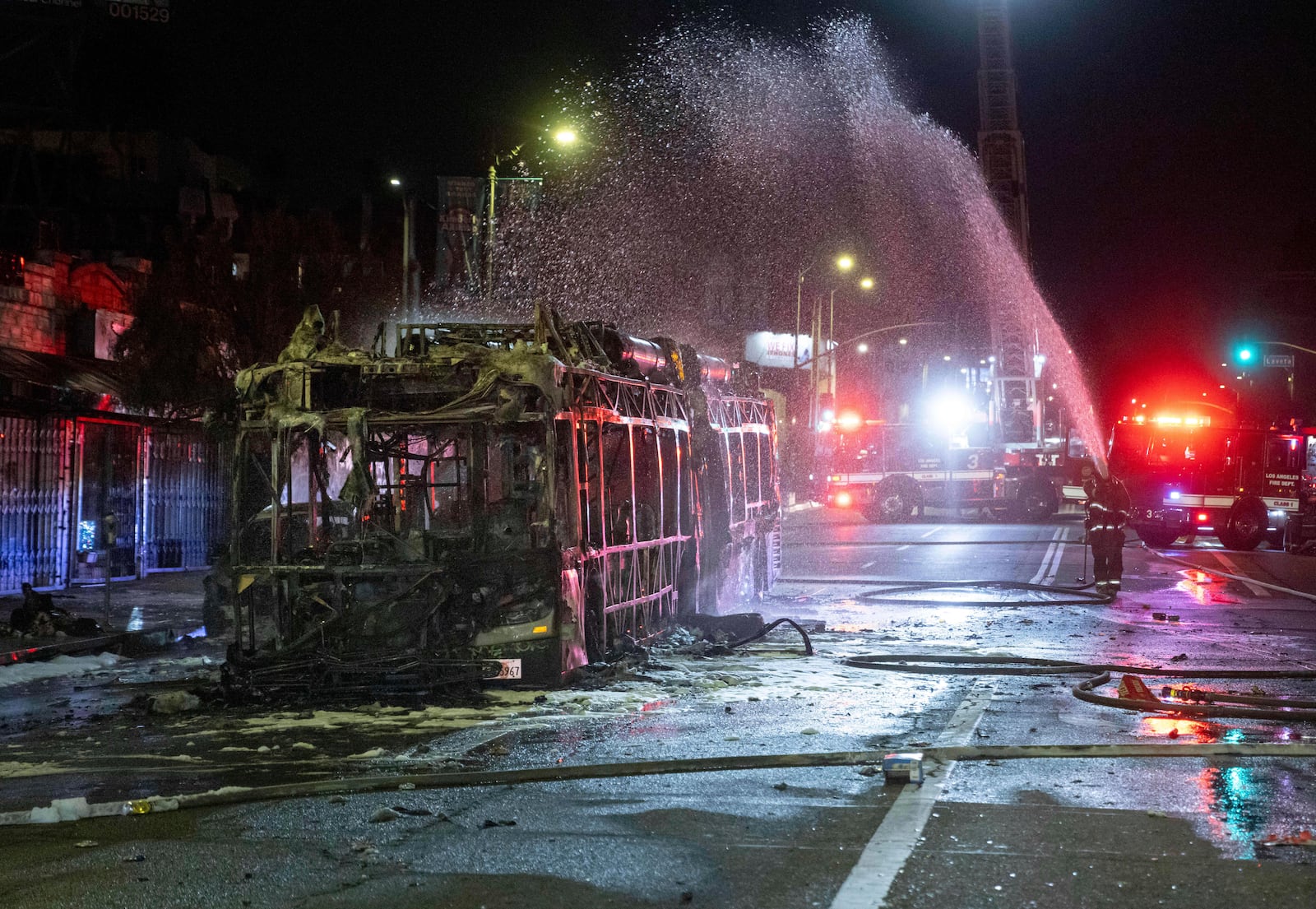 Firefighters douse water on a bus that was set on fire at Sunset and Echo Park after people gathered on the streets after the Los Angeles Dodgers defeated the New York Yankees to win the baseball World Series early Thursday, Oct. 31, 2024, in Los Angeles. (AP Photo/Ethan Swope)