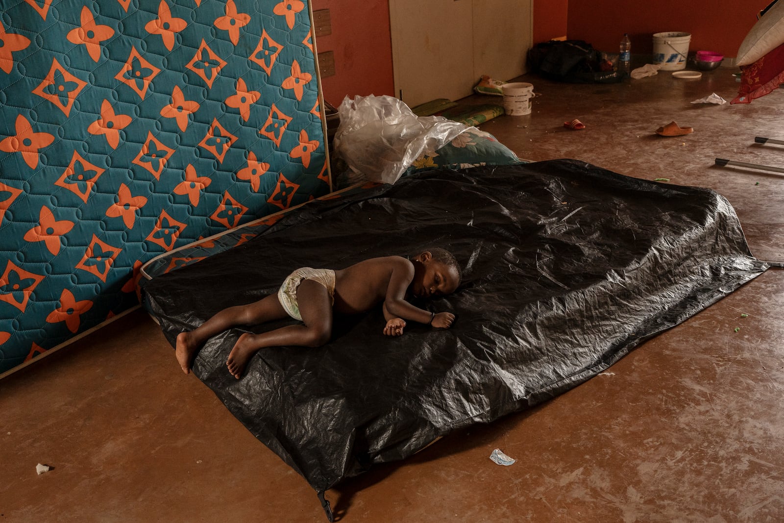 A child sleeps at the Lycée des Lumières where he found refuge, Thursday, Dec. 19, 2024 in Mamoudzou, Mayotte, (AP Photo/Adrienne Surprenant)