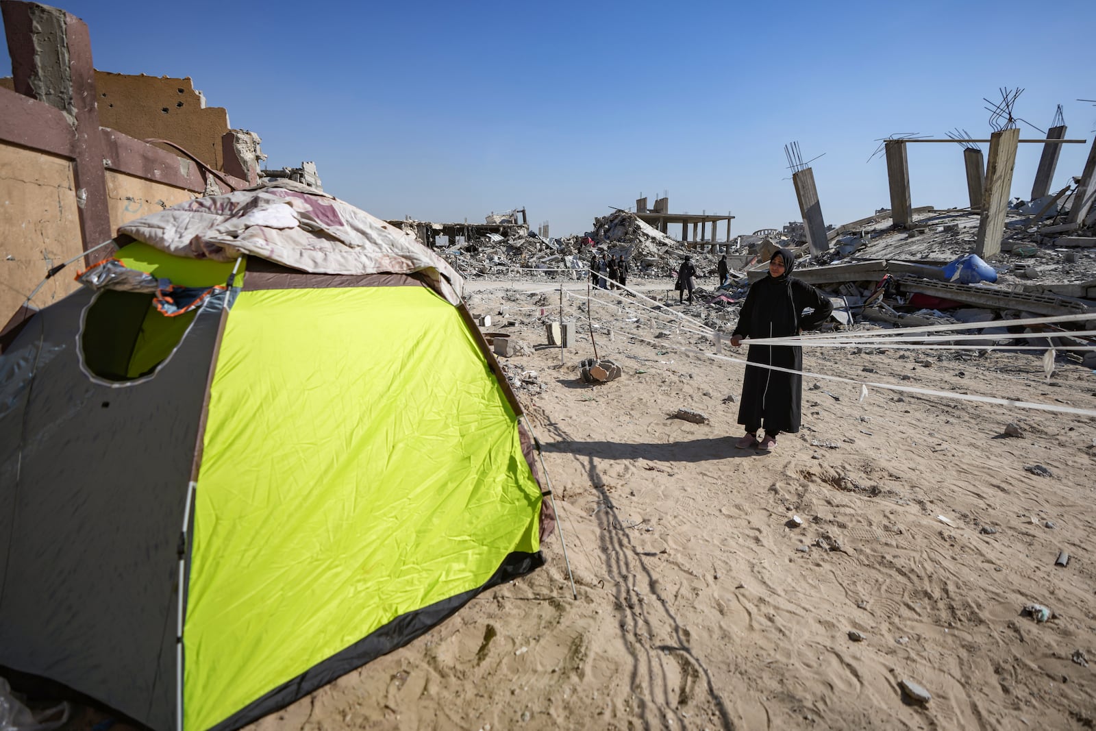 Manual Aslim stands next to a tent, she set up in front of her destroyed home, days after the ceasefire deal between Israel and Hamas came into effect, in Rafah, southern Gaza Strip, Tuesday, Jan. 21, 2025. (AP Photo/Abdel Kareem Hana)